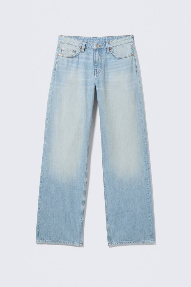 Vue de FACE d'une paire de jeans bleu clair taille basse, présentant une coupe ample et large avec une longueur longue. Ils arborent un design classique à 5 poches avec une fermeture éclair, et le denim montre un délavage subtil, plus clair au niveau des cuisses. - 1