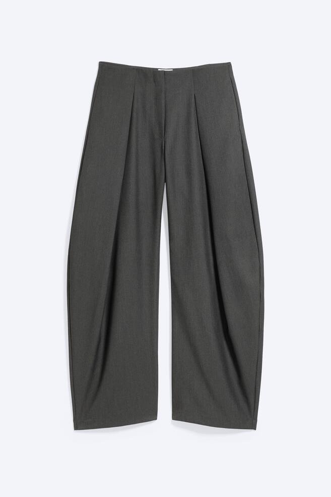 Diese von vorn gezeigten dunkelgrauen Balloon-Hosen zeichnen sich durch eine weite, geschwungene Silhouette mit tiefen Falten vorne aus, die einen voluminÃ¶sen Fall erzeugen. Das Design zeigt einen klaren Bund mit verdecktem Frontverschluss und weite, leicht zulaufende SÃ¤ume. - 1