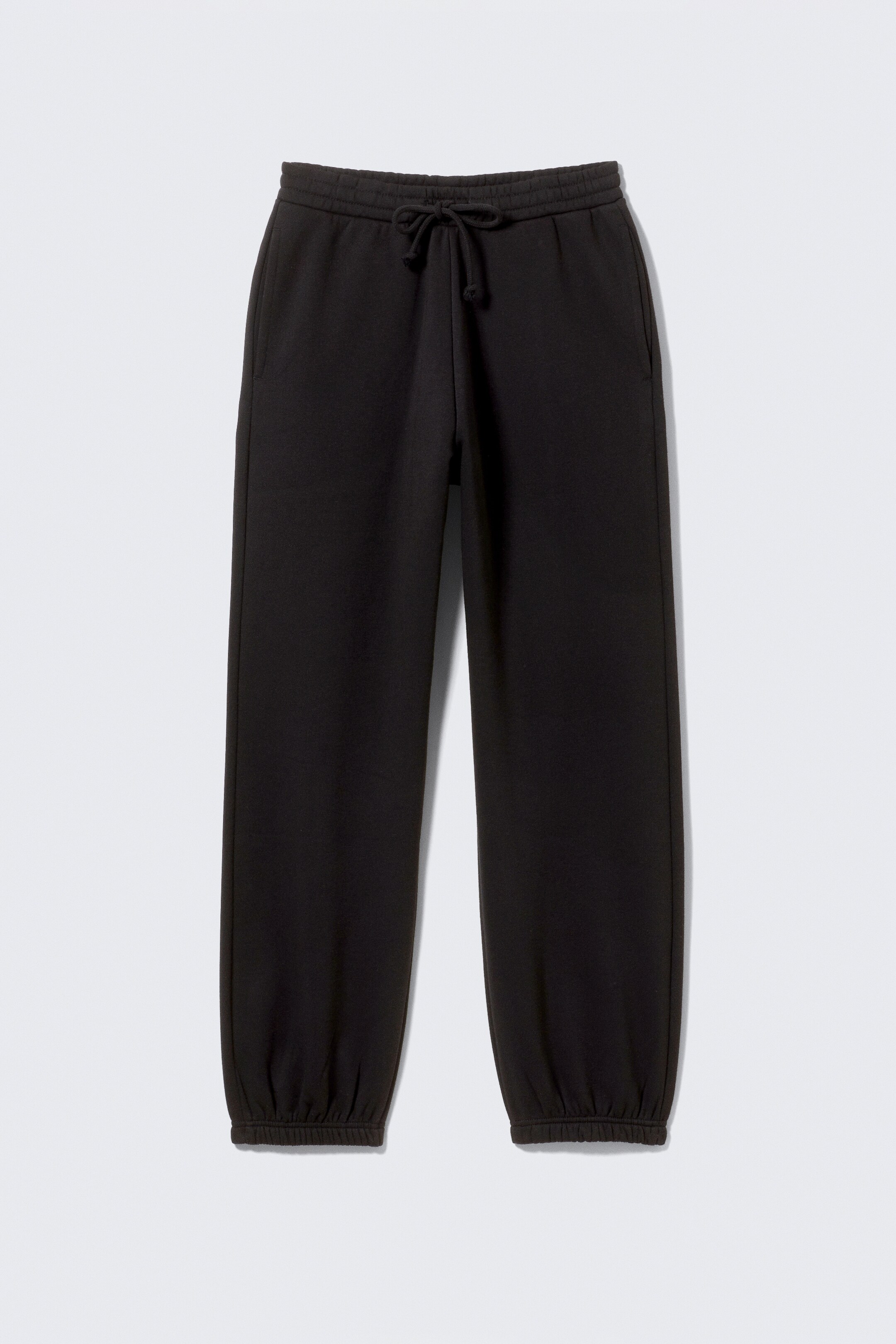 Ingrandisci l'immagine: Un paio di pantaloni della tuta neri è presentato FRONTE. Sono caratterizzati da una cintura elasticizzata con cordoncini visibili, tasche a filo laterali e polsini elasticizzati raccolti.