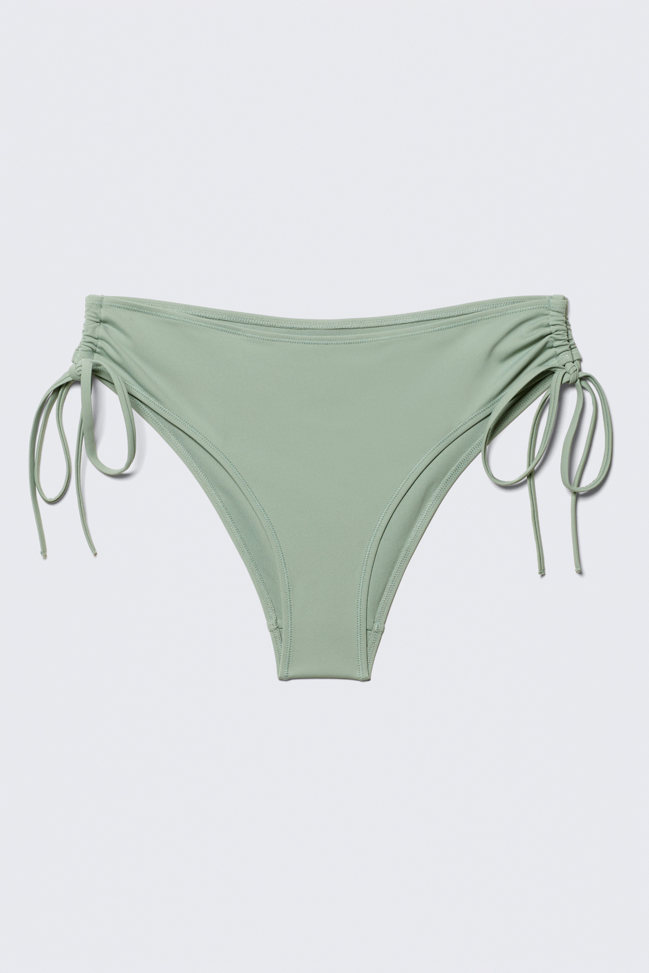 Visualizza immagine più grande: Un bikini bottom verde chiaro è presentato con una vista frontale, caratterizzato da dettagli arricciati sui lati con lacci regolabili.