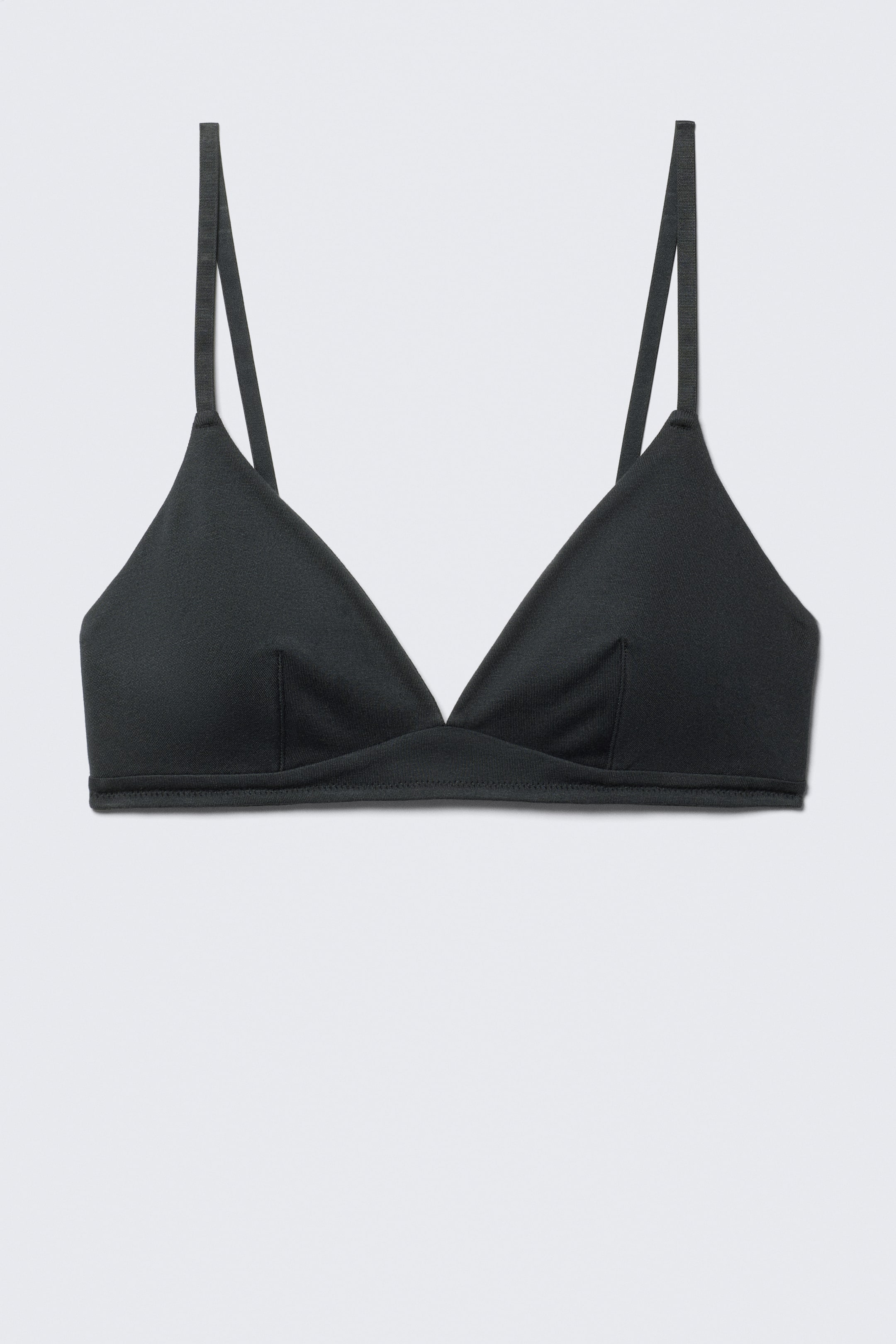 View larger image: A black bralette is presenting FRONT, featuring triangular cups with vertical seams and thin spaghetti straps. A flat, stitched band is forming the base of the garment.