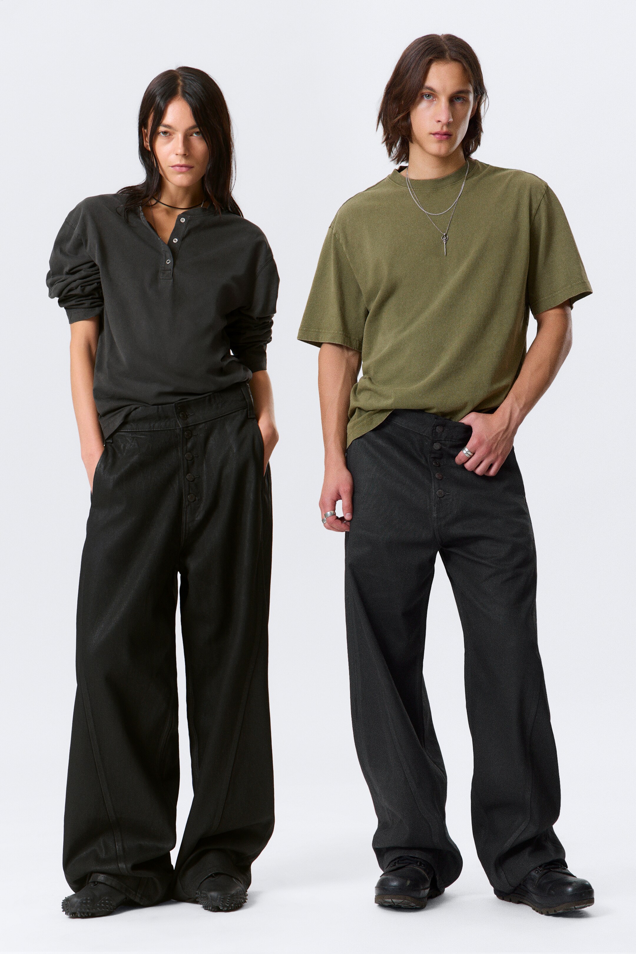 Größeres Bild anzeigen: Eine Hose mit dunkler Waschung und weitem Schnitt wird VON VORNE präsentiert, mit einem weiten Bein und einem sauberen Bund. Die Jeans sind mit einem sichtbaren Knopfverschluss, geschwungenen vorderen Aufgesetzttaschen und tonalen Zwillingsnähten designt, was zu ihrem von der Arbeitskleidung inspirierten Ästhetik beiträgt.