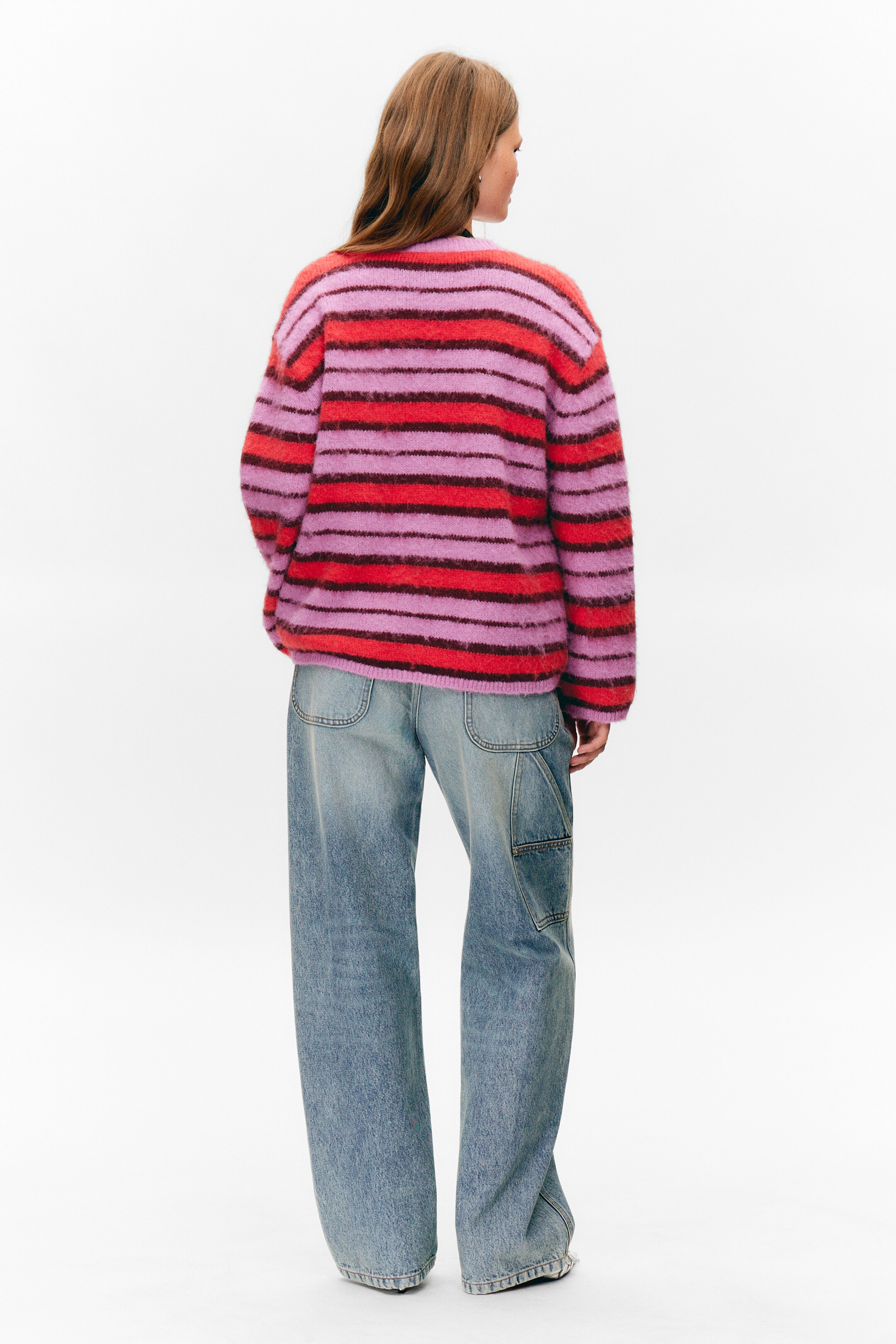 Größeres Bild anzeigen: Ein flauschiger Strickpullover wird von hinten präsentiert, mit breiten horizontalen Streifen in Rot, Flieder und Dunkelrot. Er zeigt eine entspannte Passform.