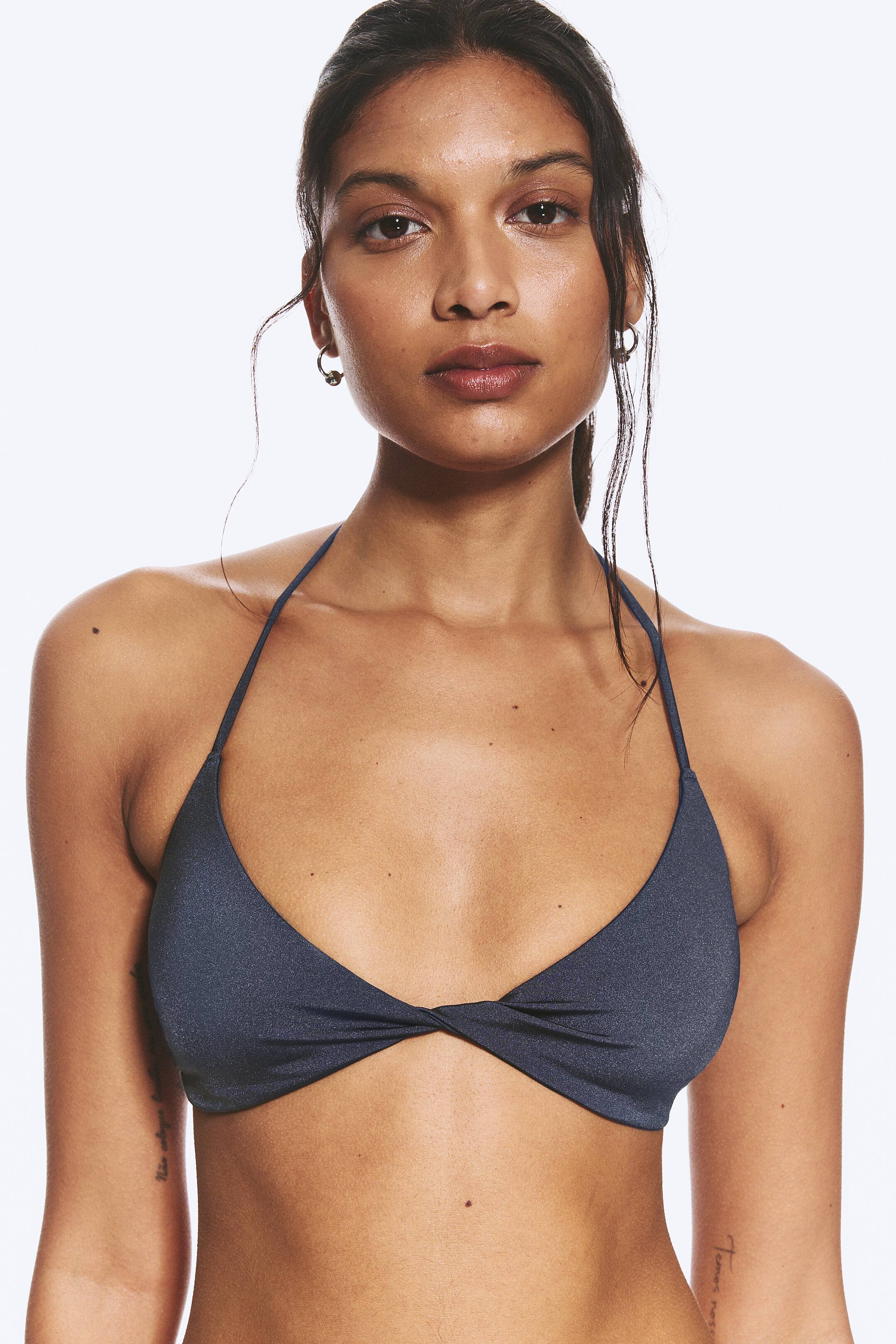 Agrandir l'image: Un haut de bikini à col licou gris foncé scintillant est présenté de face, avec des bonnets triangulaires et un détail de nœud torsadé au centre avant.