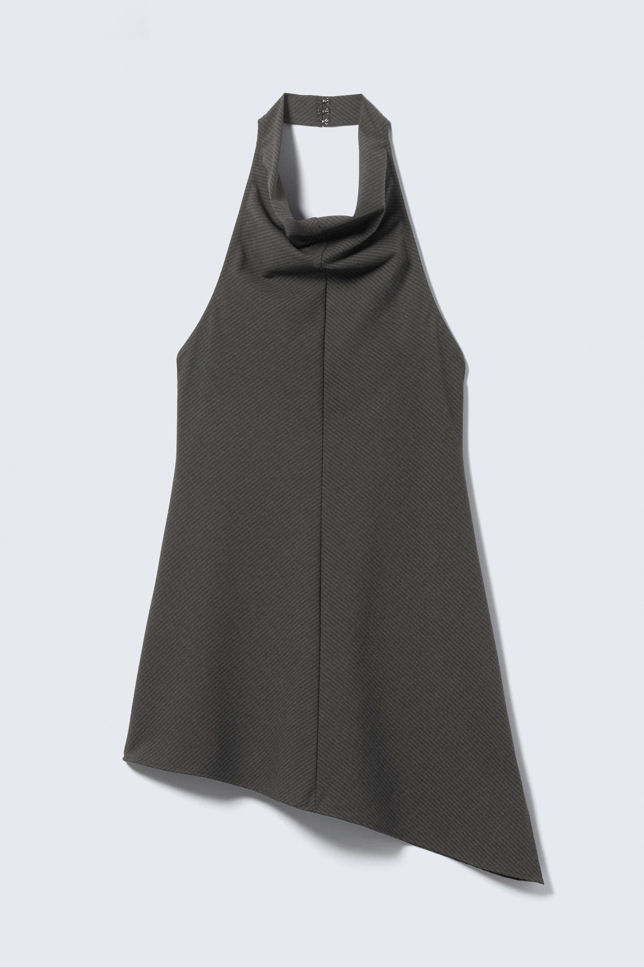 Größeres Bild ansehen: Ein anthrazitgraues Neckholder-Top ist von vorne zu sehen und zeichnet sich durch einen drapierten Wasserfallausschnitt und ein dezentes diagonales Rippmuster im gesamten Stoff aus. Es ist mit einem ärmellosen Schnitt und einem asymmetrischen Saum gestaltet, der auf der rechten Seite länger ist, während drei Haken- und Ösenverschlüsse den Nackenriemen sichern.