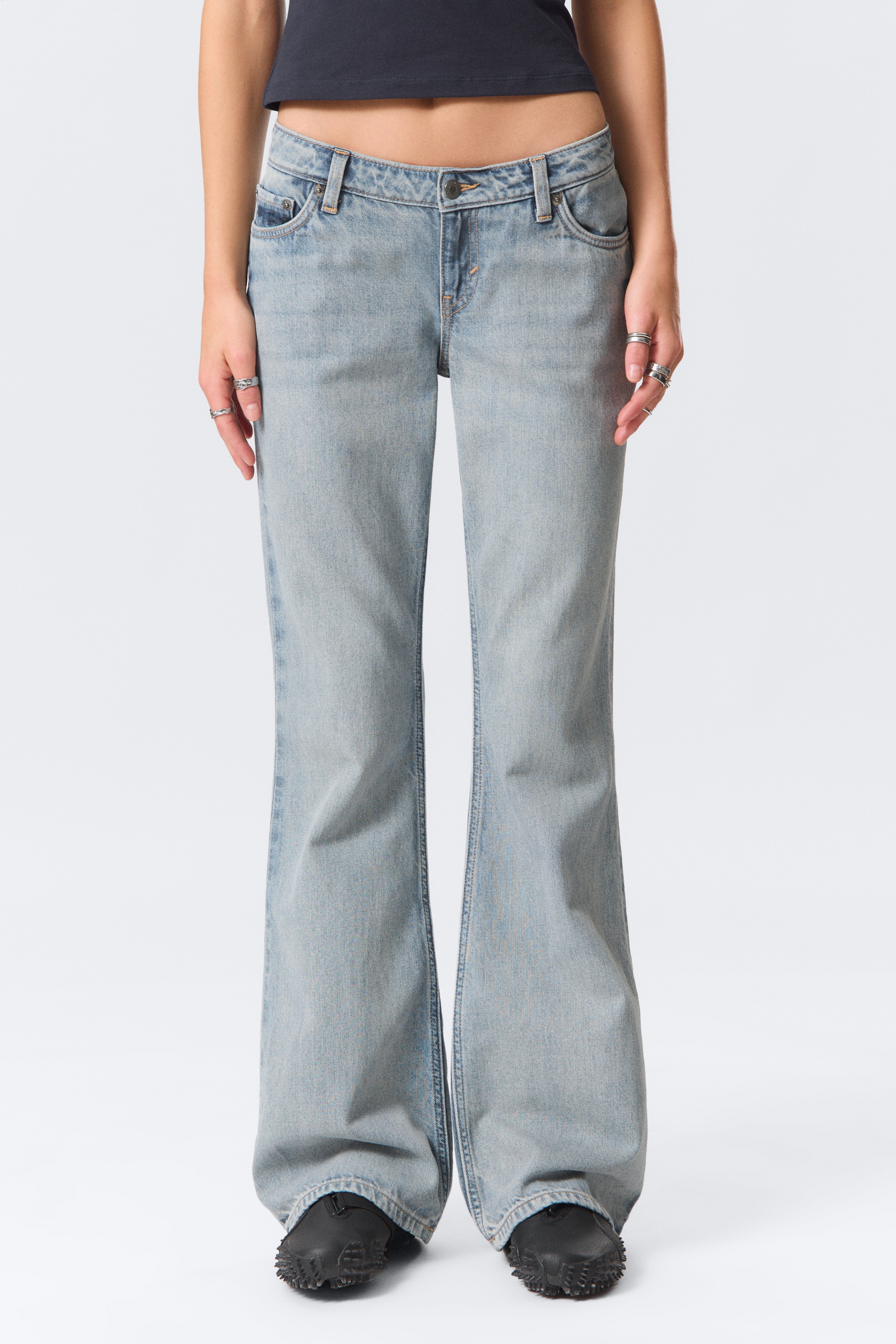 Visualizza immagine più grande: I jeans in denim a lavaggio chiaro sono presentati in vista frontale, con una vita bassa e una gamba a zampa che si allarga dal ginocchio in giù. I jeans sono progettati con una vestibilità rilassata attraverso la coscia e presentano passanti per cintura, una chiusura con bottone e tasche anteriori a cucchiaio.