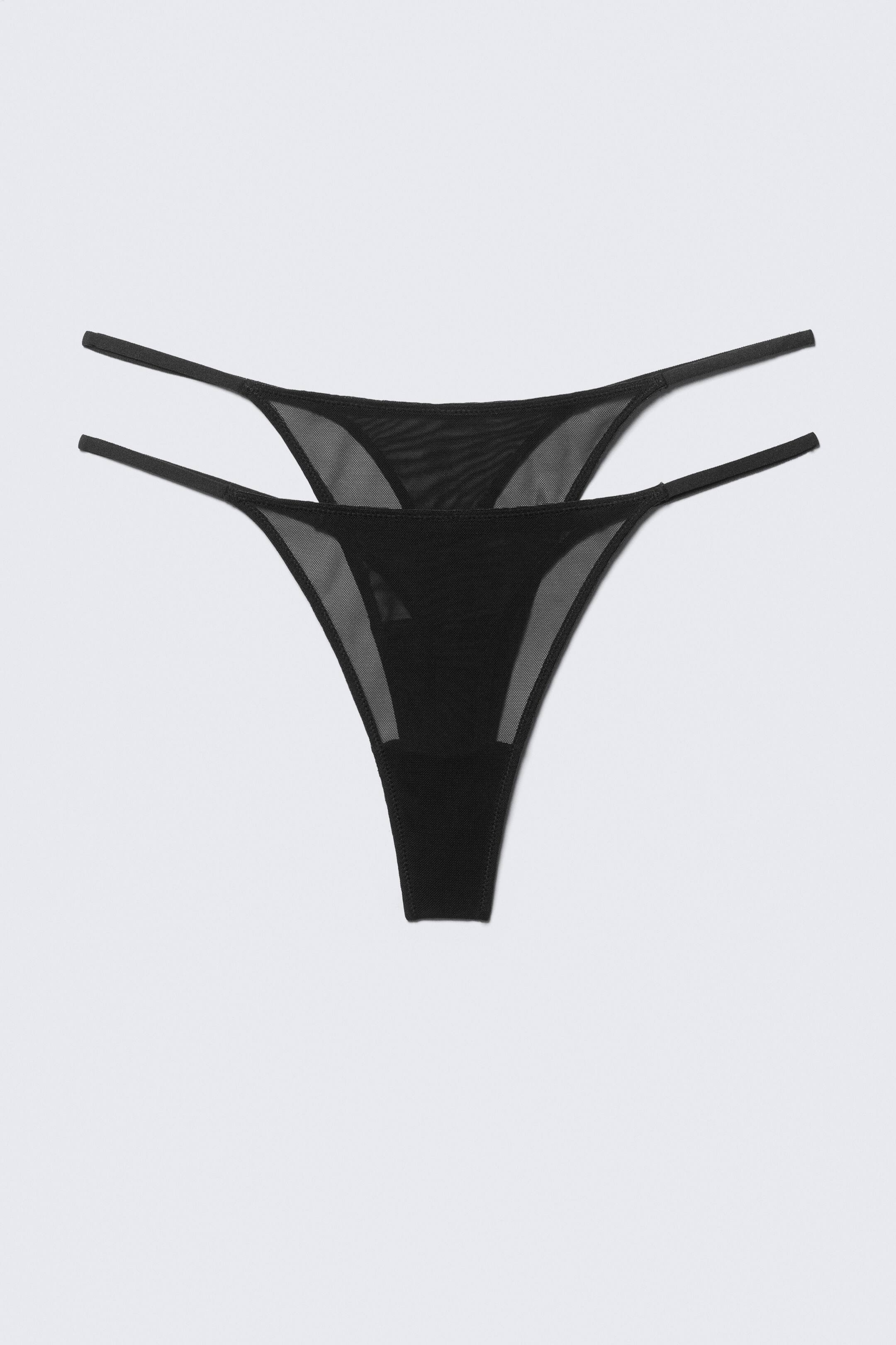 Grotere afbeelding bekijken: Een zwarte string wordt VOORAAN gepresenteerd, met een doorschijnend mesh driehoekig voorpaneel en een ondoorzichtige kruis, en dubbele elastische bandjes die vanuit de bovenste hoeken uitstrekken.