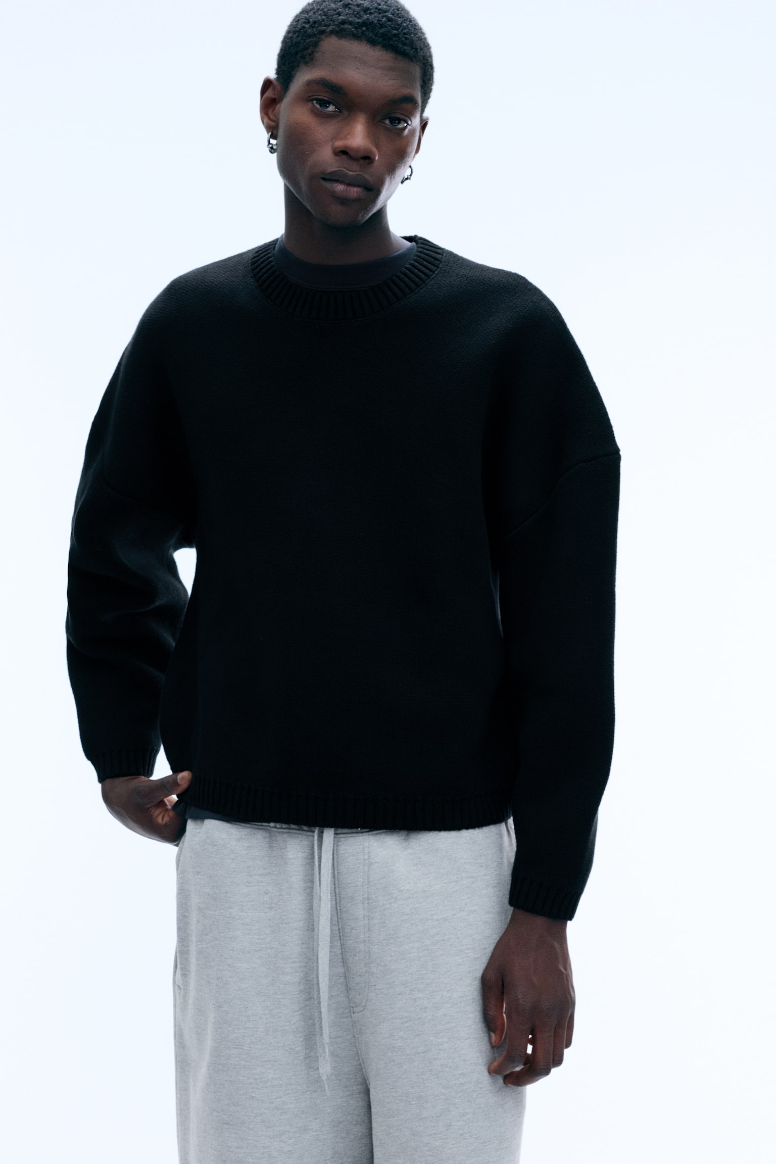 Ein schwarzer Strickpullover präsentiert seine VORDERSEITE, mit einer übergroßen Passform, überschnittenen Schultern, einem Rundhalsausschnitt und gerippten Abschlüssen am Hals, an den Bündchen und am Saum. Ein weißes 'WEEKDAY'-Label ist am inneren Rundhalsausschnitt sichtbar. - 1