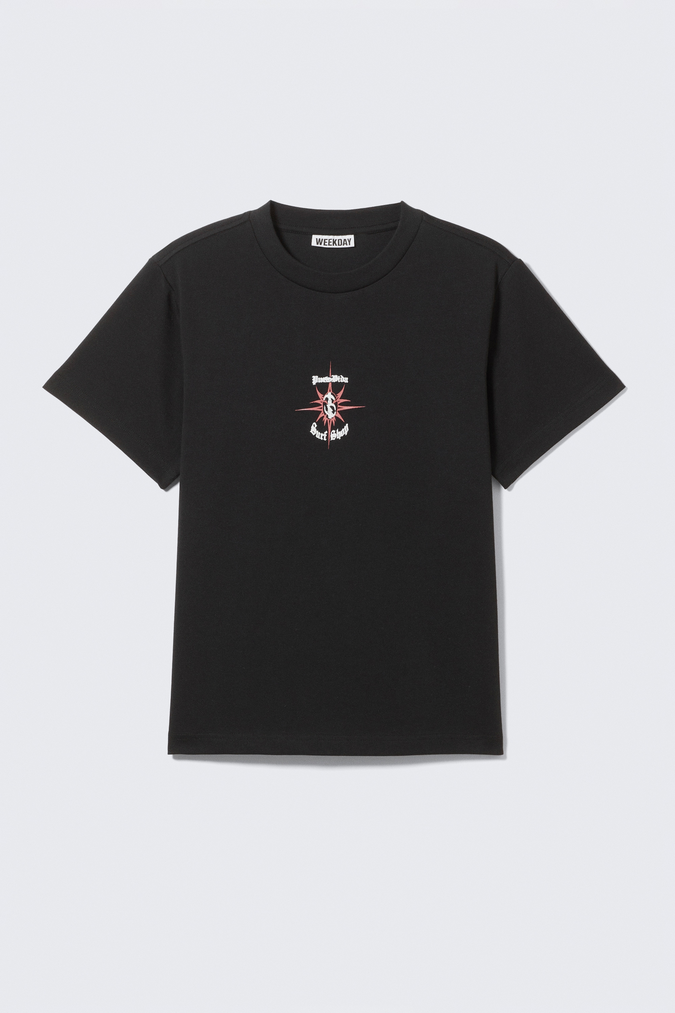 View larger image: A black short-sleeved crew neck t-shirt is lying flat, facing forward. It is featuring a red and pink starburst graphic with a dollar sign at its center, flanked by white gothic text reading 'Peace & Love' above and 'Surf Shop' below.