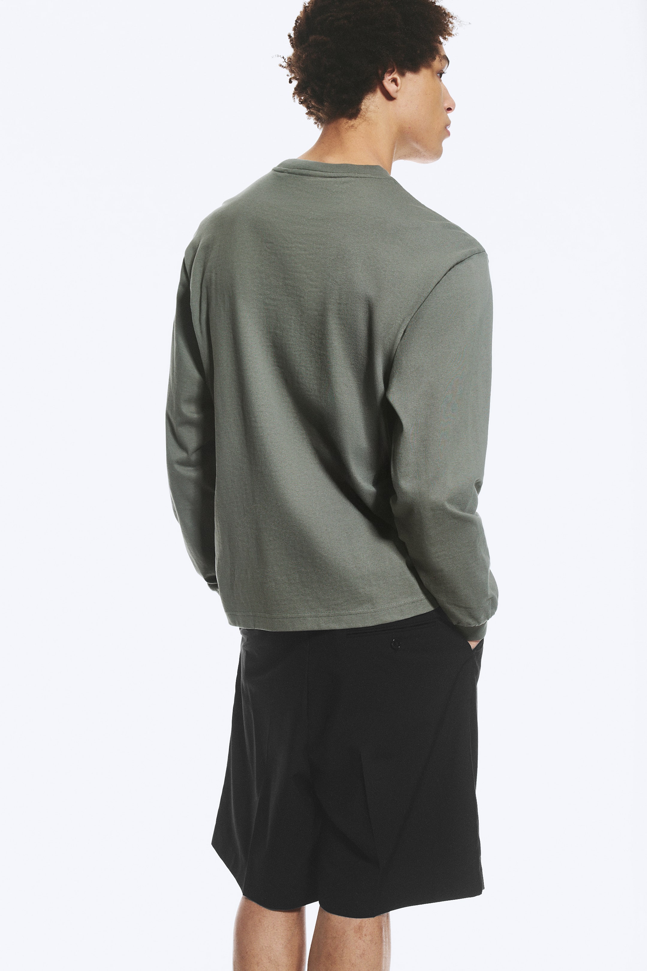 Ver imagen más grande: La camiseta de manga larga verde oliva con cuello redondo se presenta desde un ángulo trasero derecho, destacando un ajuste relajado, una tela suave y mangas largas lisas.