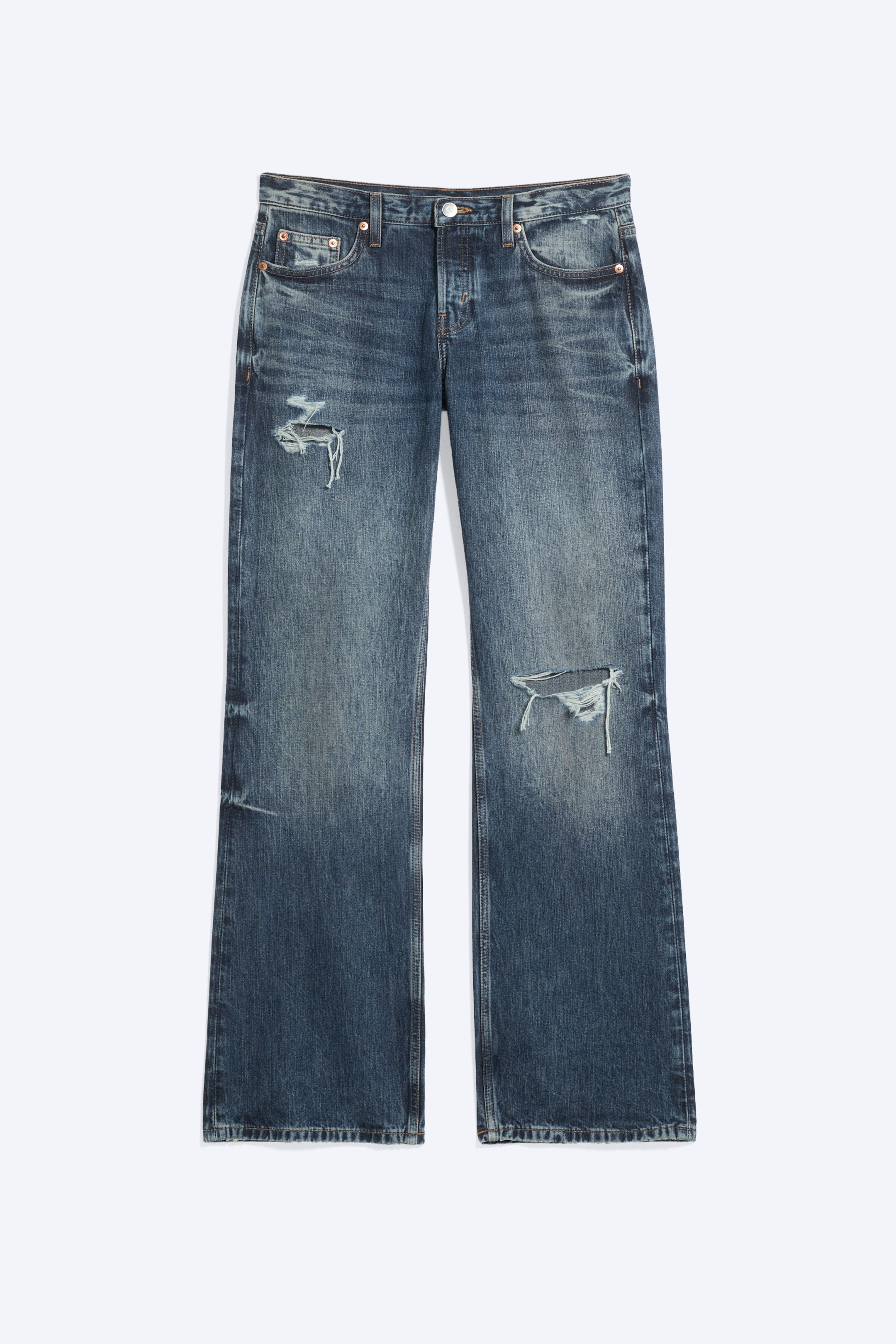 Zobacz większy obraz: Niskostanowe jeansy o swobodnym kroju z nogawką bootcut w spranym niebieskim odcieniu, pokazane z przodu, z klasycznym pięciokieszeniowym fasonem, efektem whiskering oraz przetarciami na prawym górnym udzie i lewym kolanie.