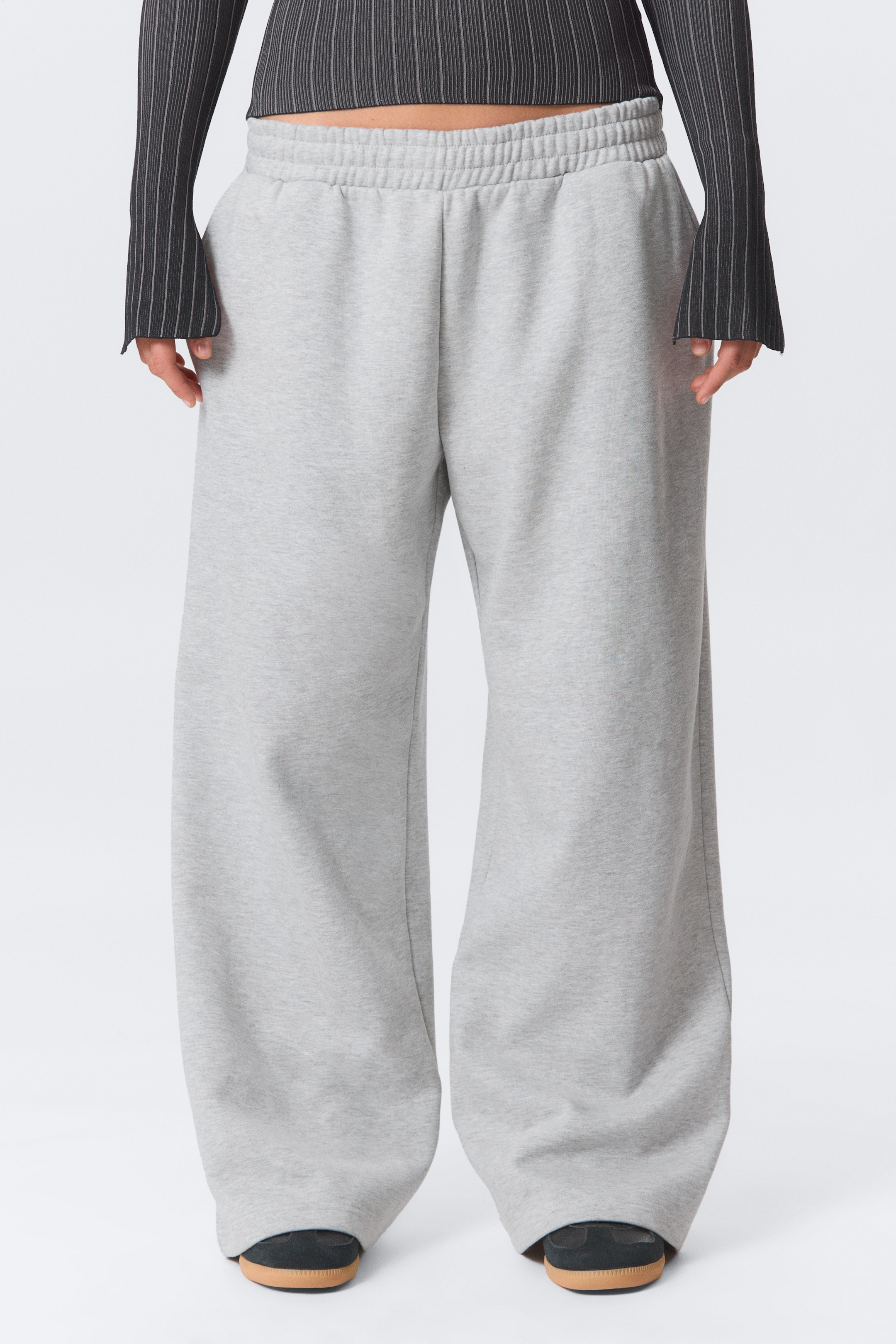 Agrandir l'image: Un pantalon de survêtement gris clair affiche une coupe ample et décontractée, avec des jambes larges, orientées vers l'avant. Ils présentent une taille élastiquée froncée et s'accumulent légèrement au niveau des chevilles.