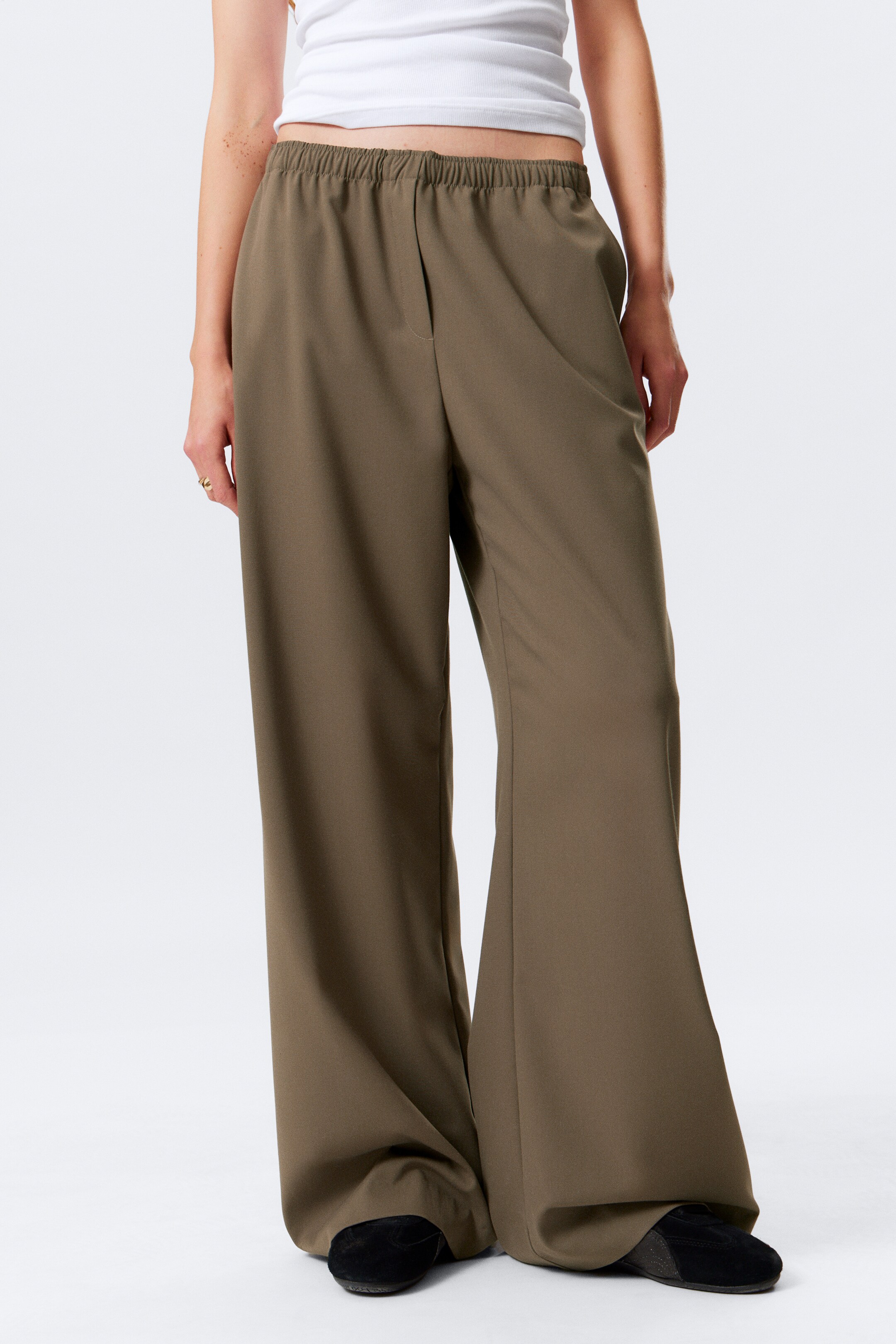Visualizza immagine più grande: I pantaloni a gamba larga verde oliva sono mostrati dalla parte anteriore. Presentano una vita elasticizzata arricciata e una vestibilità fluida e drappeggiata che si estende fino al pavimento e si accumula sopra i piedi.