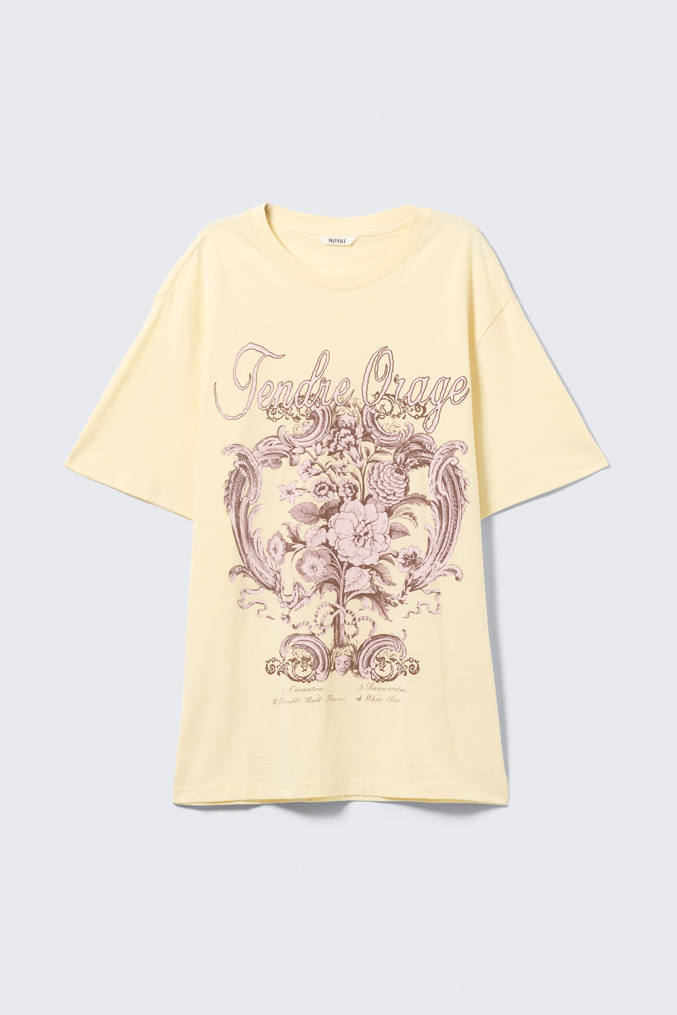 Größeres Bild ansehen: Ein blassgelbes, übergroßes T-Shirt ist von VORNE zu sehen, mit Rundhalsausschnitt und kurzen Ärmeln. Auf der Vorderseite ist ein großes Grafikdruck zu sehen, das den strukturierten Schriftzug "Tendre Orage" über einem kunstvollen Blumenarrangement mit dekorativem Rankenwerk in Brauntönen und Rosa zeigt.