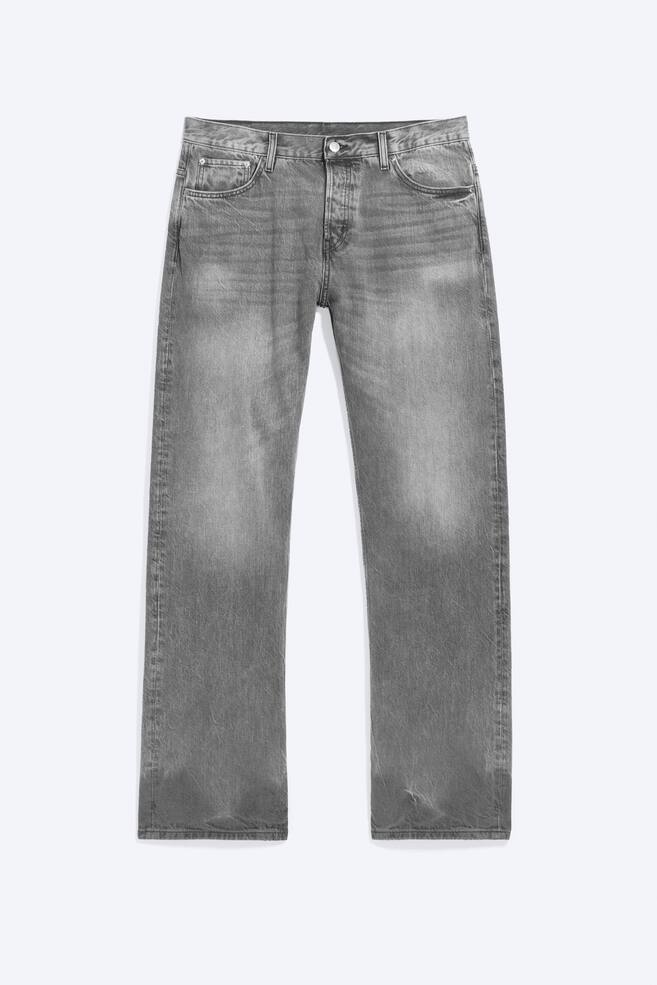 Um par de jeans cinzentos de cintura mÃ©dia estÃ¡ de frente, apresentando um corte descontraÃ­do e uma silhueta de perna direita. As calÃ§as de ganga apresentam um efeito lavado e desgastado nas coxas e ancas, um design clÃ¡ssico de cinco bolsos e um fecho de botÃ£o na cintura. - 1