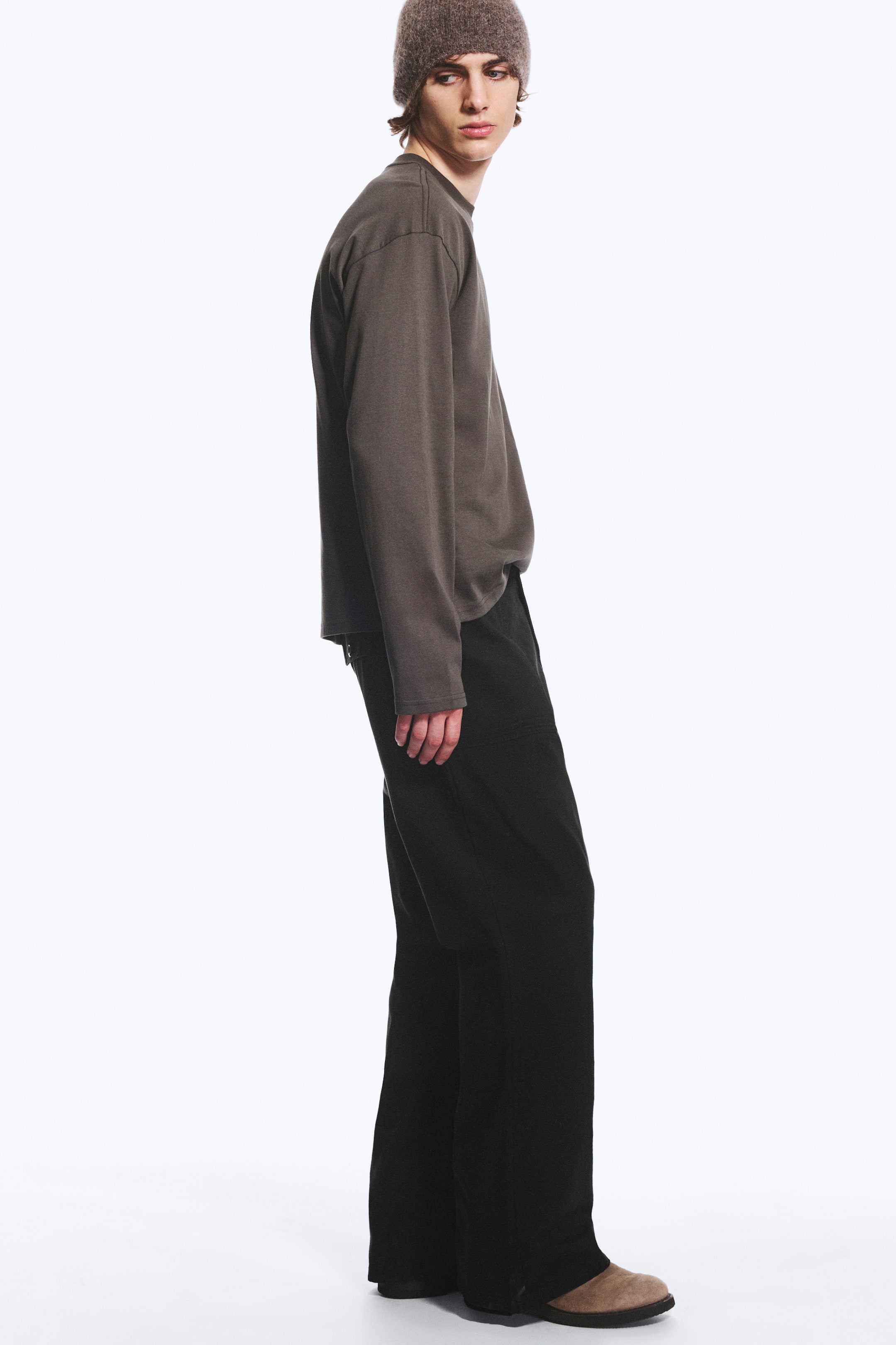 Größeres Bild anzeigen: Die schwarze Workwear-Hose aus Baumwoll-Twill mit normaler Passform und dezent ausgestelltem Bootcut-Bein wird vom Model getragen. Die Hose ist mit einem langärmeligen grauen Oberteil und braunen Schuhen kombiniert.
