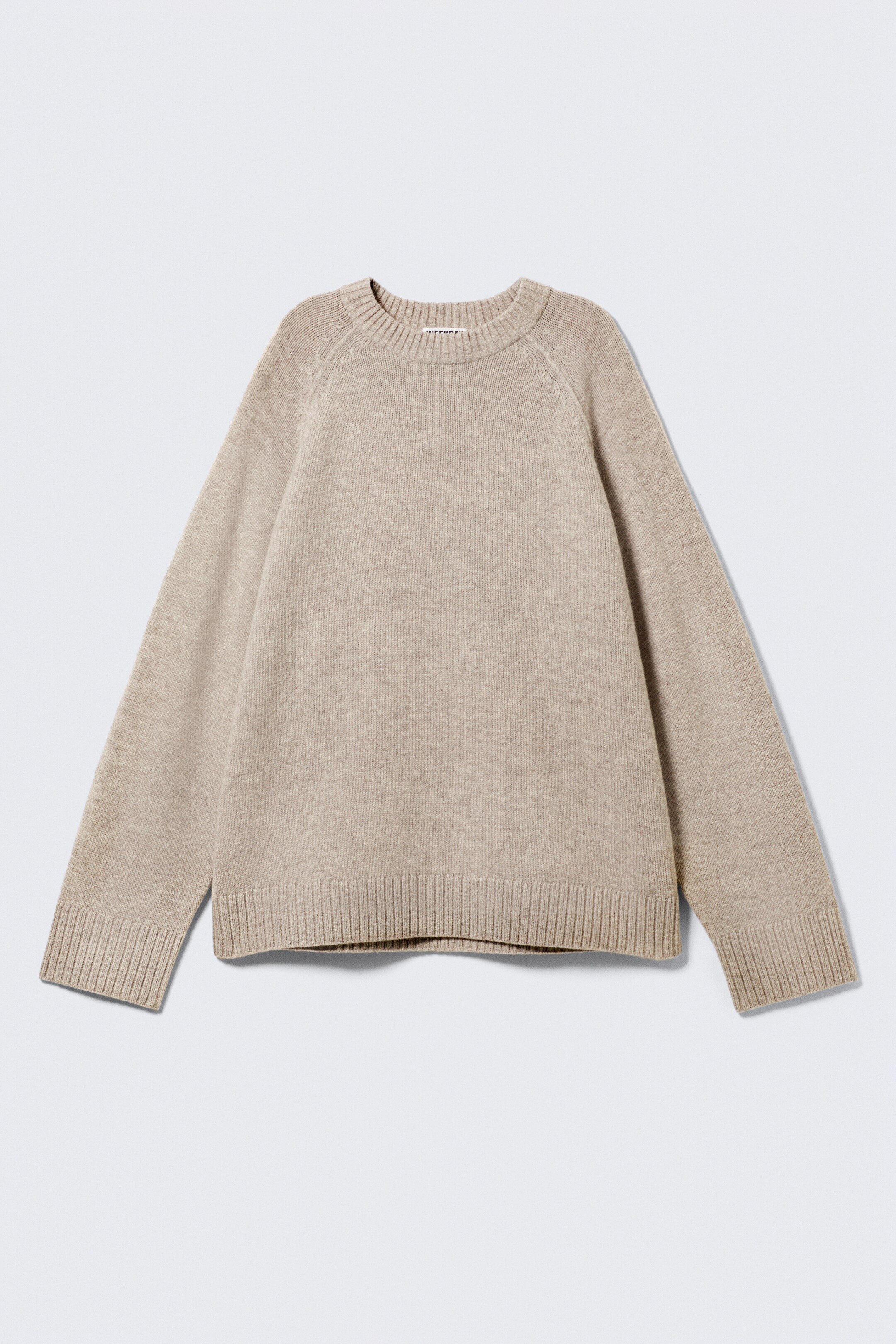 Ver imagen más grande: Un jersey de punto beige se muestra en la parte delantera, con una textura de punto fino y un corte holgado. Tiene un cuello redondo, mangas raglán y bordes acanalados anchos en los puños y el dobladillo.