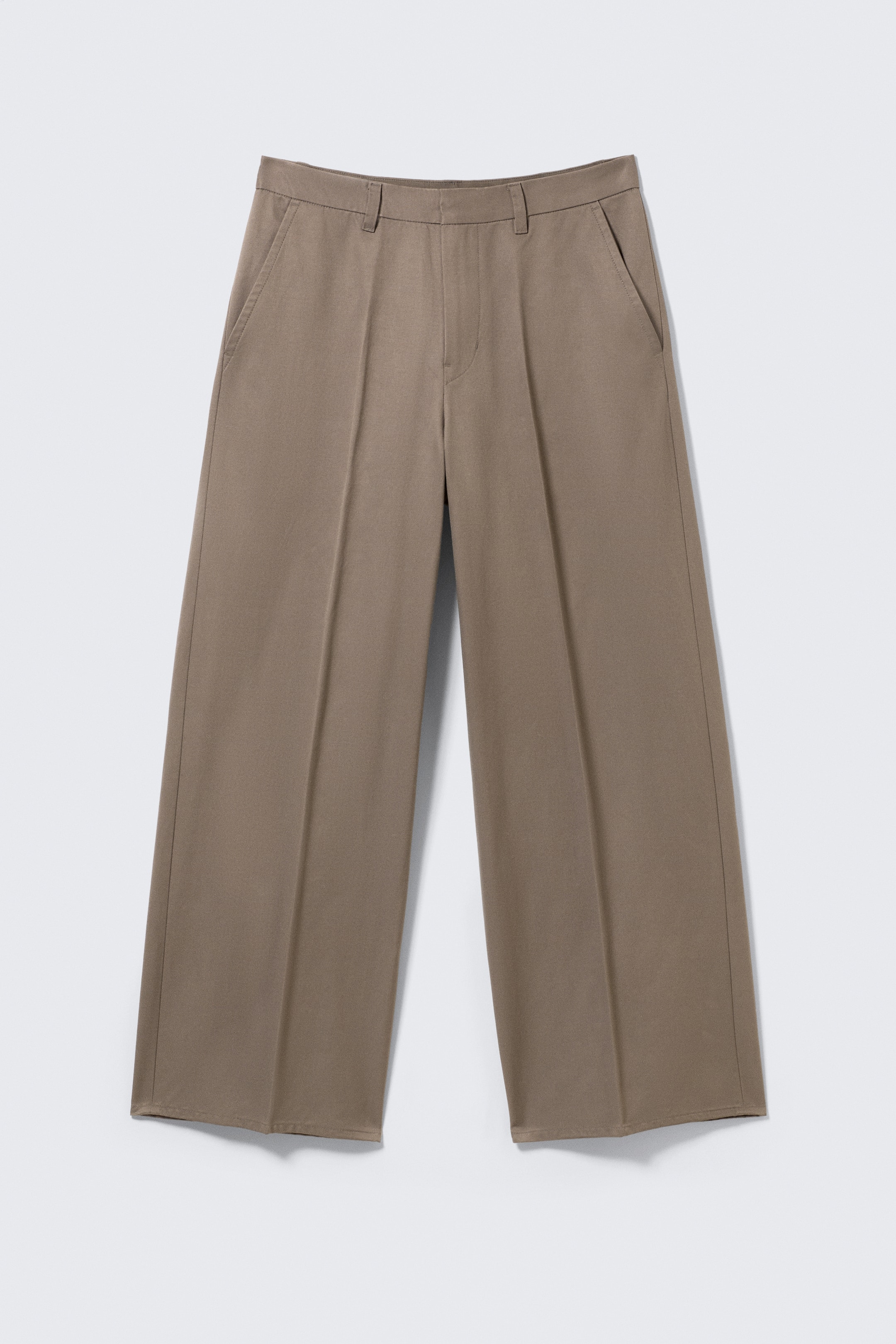 Agrandir l'image: Un pantalon chino marron clair à coupe ample est présenté de FACE. Le pantalon est confectionné en sergé structuré, doté de passants de ceinture, d'une fermeture éclair et de poches latérales en biais. Des plis marqués descendent le long de chaque jambe large.