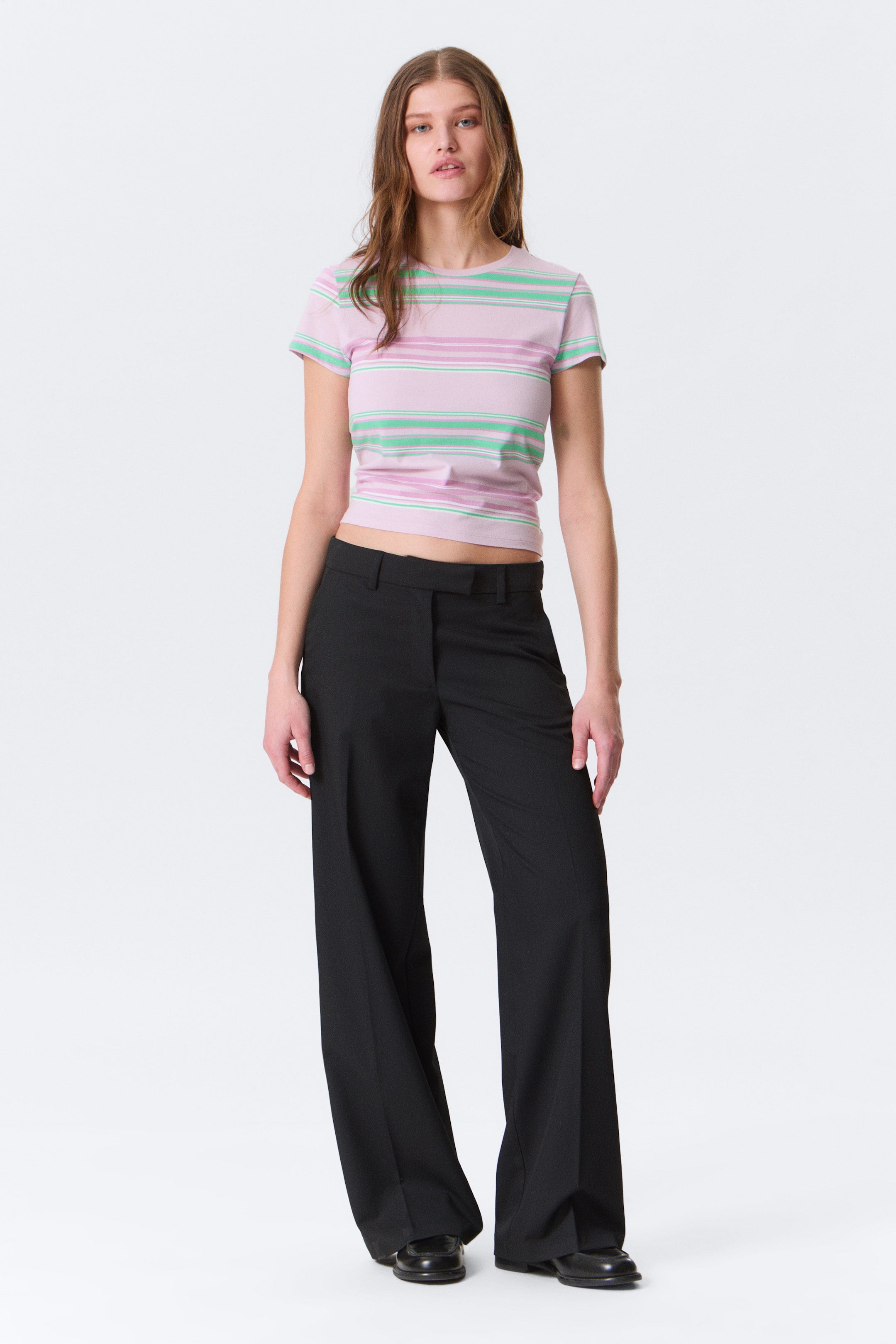 Agrandir l'image: Pantalon noir sur mesure avec une coupe large et une taille mi-haute dotée de passants de ceinture visibles. Ils présentent un pli marqué sur le devant de chaque jambe et s'étendent sur toute la longueur.