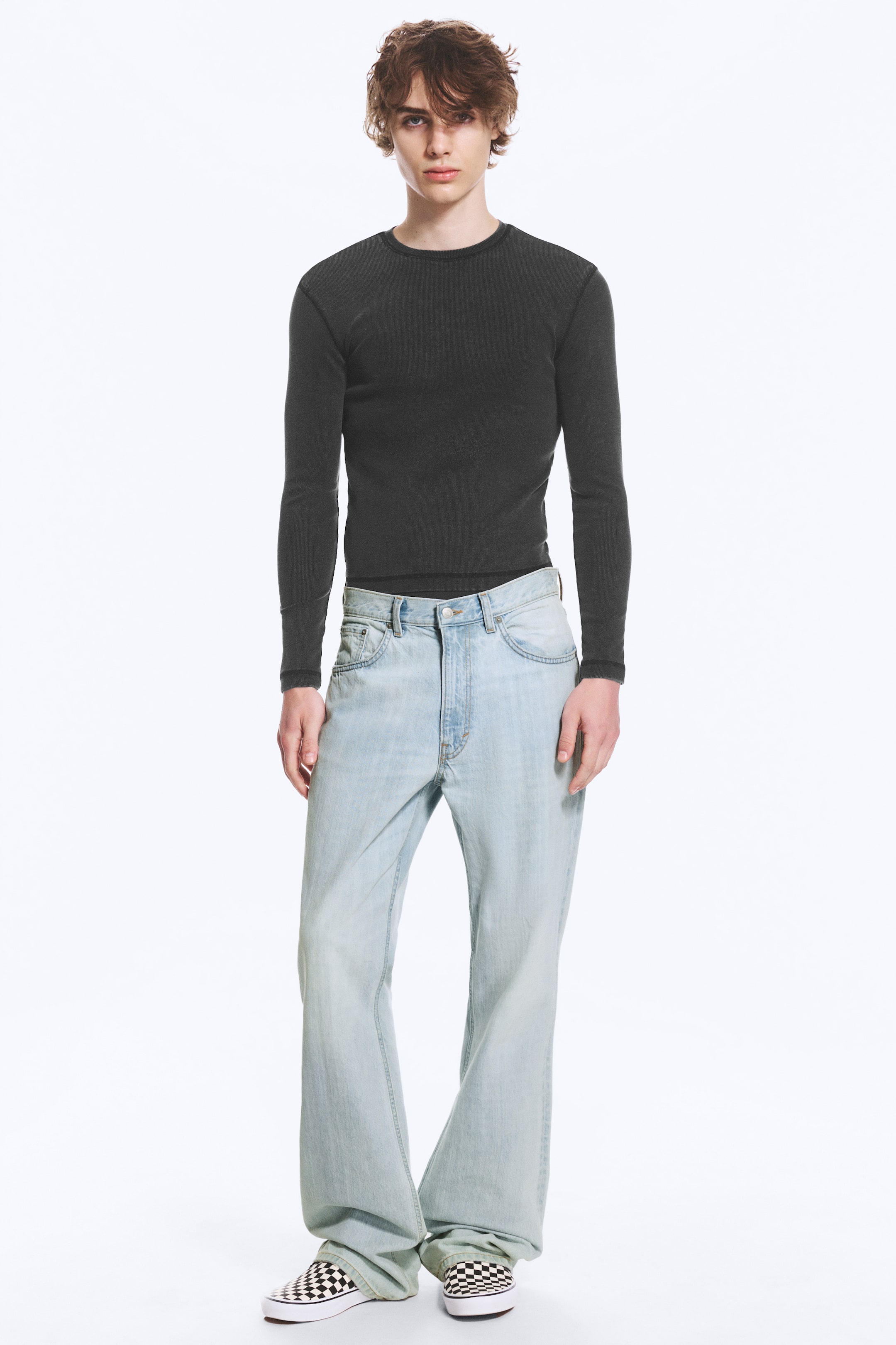 Größeres Bild anzeigen: Das dunkelgraue, langärmelige Thermo-Shirt mit Rundhalsausschnitt und schmaler Passform besticht durch sichtbare Nahtdetails. Die hell gewaschenen Denim-Jeans präsentieren sich mit einem entspannten, weiten Bein und einem klassischen Knopf- und Reißverschluss.