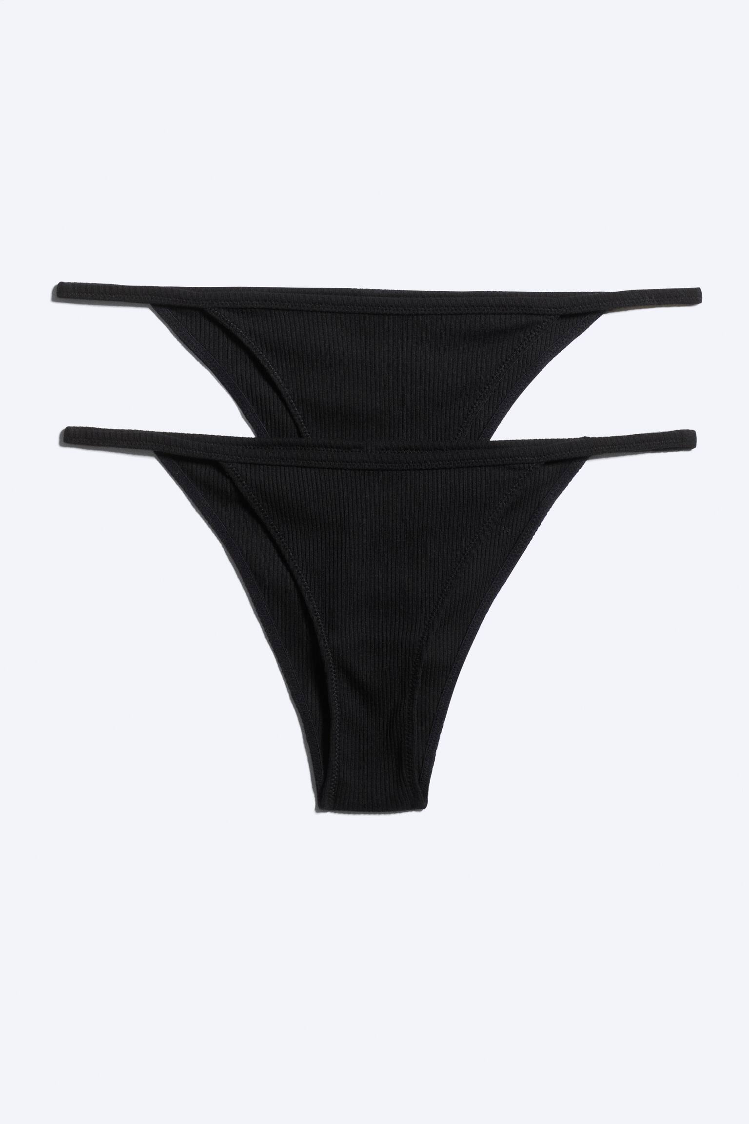 Kaksi paria mustia ribbikankaisia string-alushousuja on aseteltu tasaisesti etupuoli ylÃ¶spÃ¤in, ja toinen pari on sijoitettu hieman toisen ylÃ¤puolelle. Molemmissa pareissa on pystysuuntainen ribbipinta, kolmionmuotoinen etupaneeli ja ohuet, joustavat string-sivunauhat.