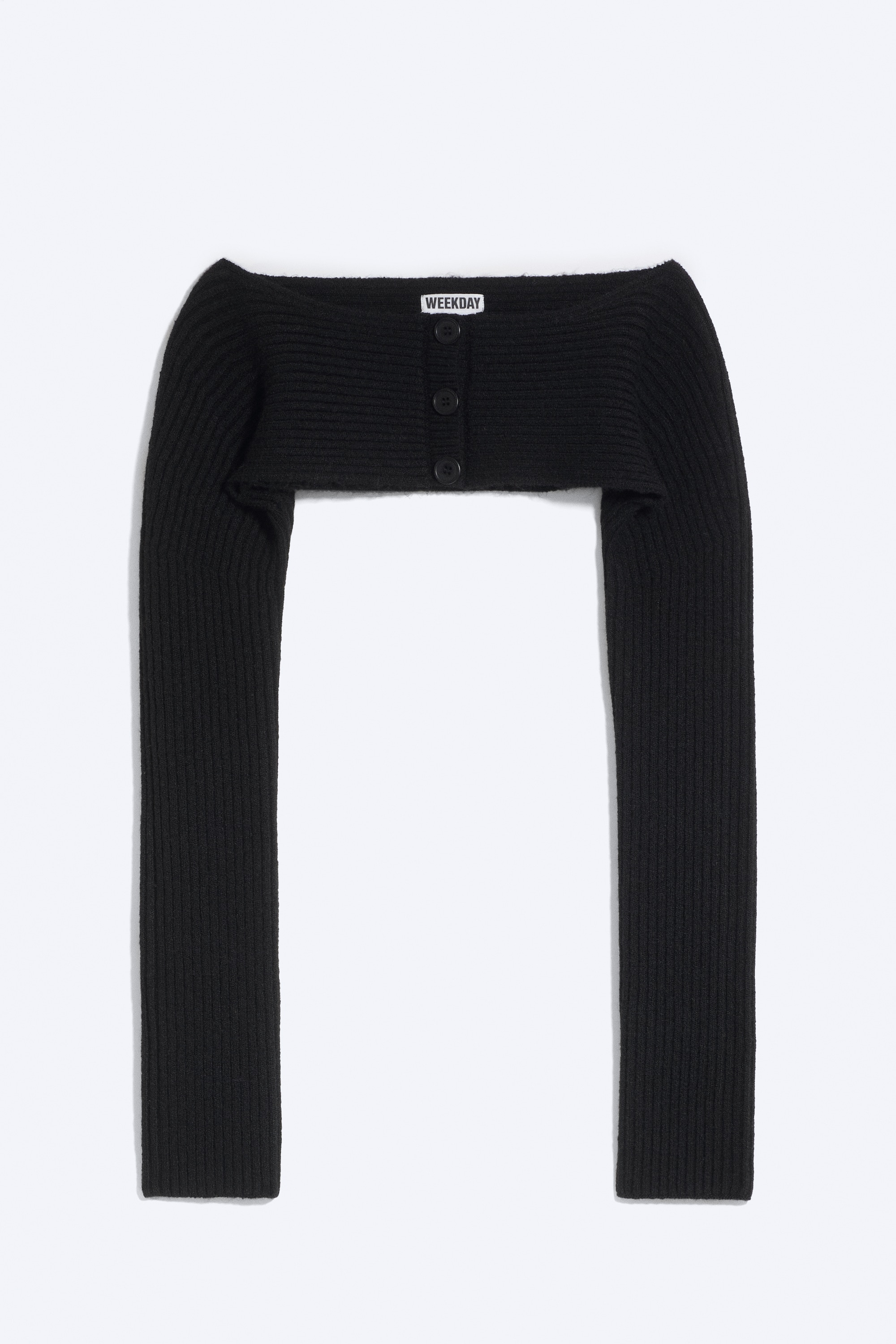 En svart bolero-cardigan i ribbestrikk med lange ermer og knappelukking foran bÃ¦res av modellen, lagt over en svart stroppelÃ¸s topp.