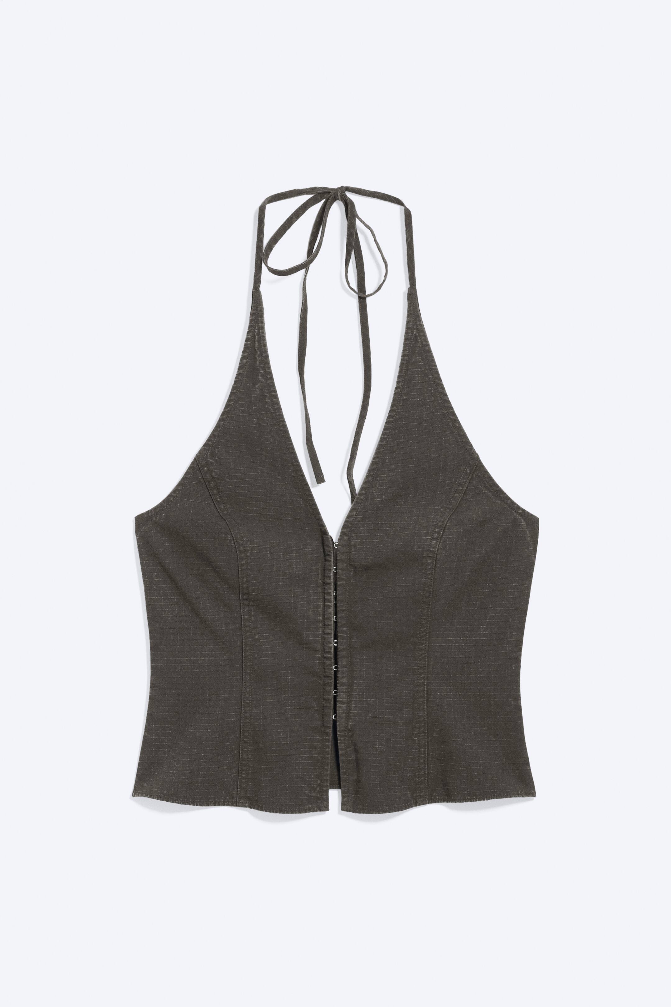 Grösseres Bild ansehen: Ein dunkelgraues Neckholder-Top zeigt eine dezente Gitterstruktur und einen tiefen V-Ausschnitt, mit dünnen Trägern, die im Nacken gebunden werden. Es verfügt über eine Reihe von Haken- und Ösenverschlüssen entlang der Vorderseite und vertikale Nähte, die das Mieder formen.