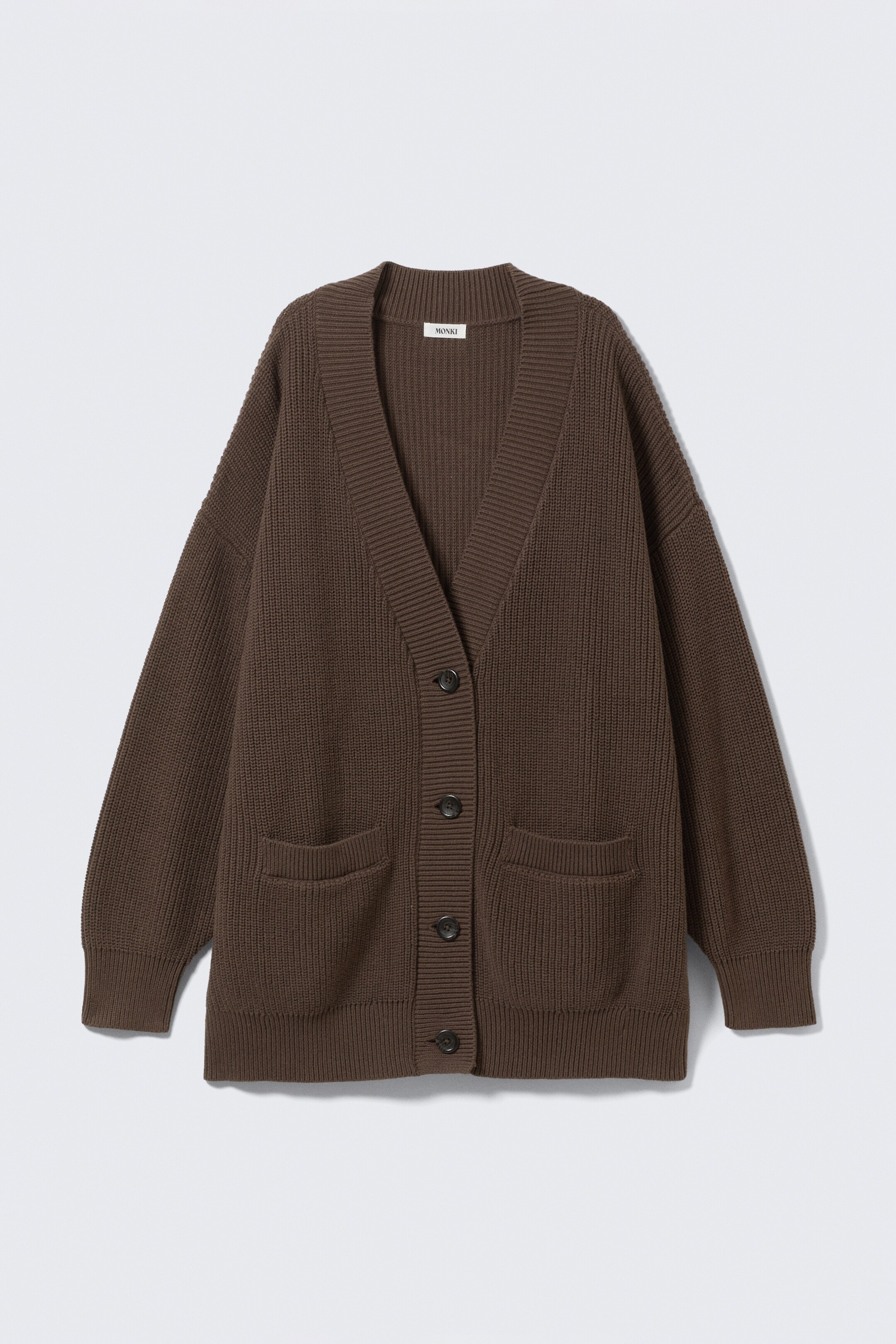 Ingrandisci l'immagine: Un cardigan marrone a maglia è disteso in piano e rivolto in avanti, con scollo a V, chiusura frontale a cinque bottoni scuri, due tasche frontali applicate, polsini a coste e orlo a coste.