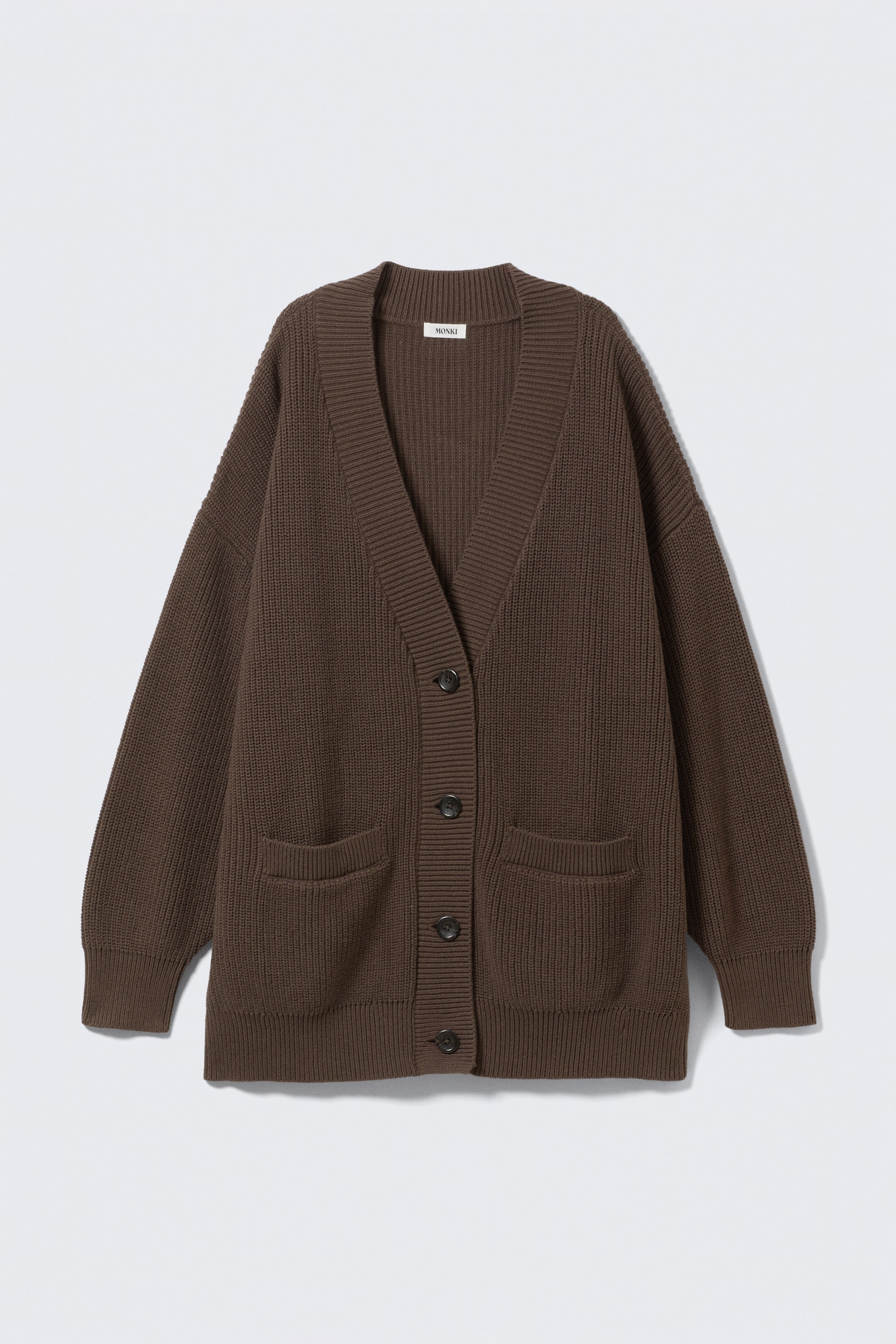Grösseres Bild ansehen: Eine braune Strickjacke liegt flach und ist nach vorne gerichtet, mit einem V-Ausschnitt, einer fünfknöpfigen Frontverschluss mit dunklen Knöpfen, zwei aufgesetzten Fronttaschen, gerippten Bündchen und einem gerippten Saum.