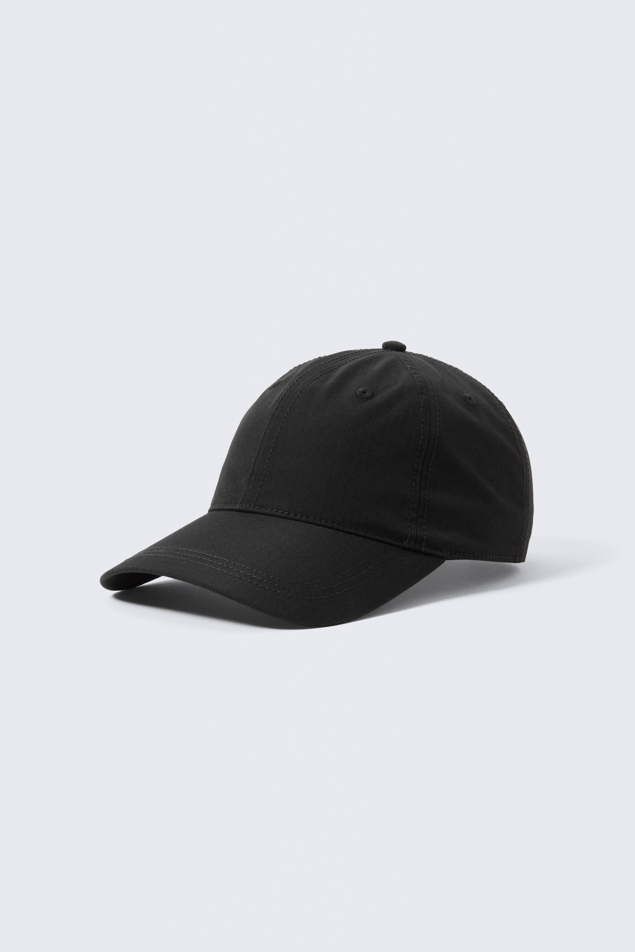 Agrandir l'image: Une casquette de baseball noire est présentée de face et de côté, mettant en avant une couronne à six panneaux avec un bouton supérieur, une visière incurvée et des œillets de ventilation visibles.