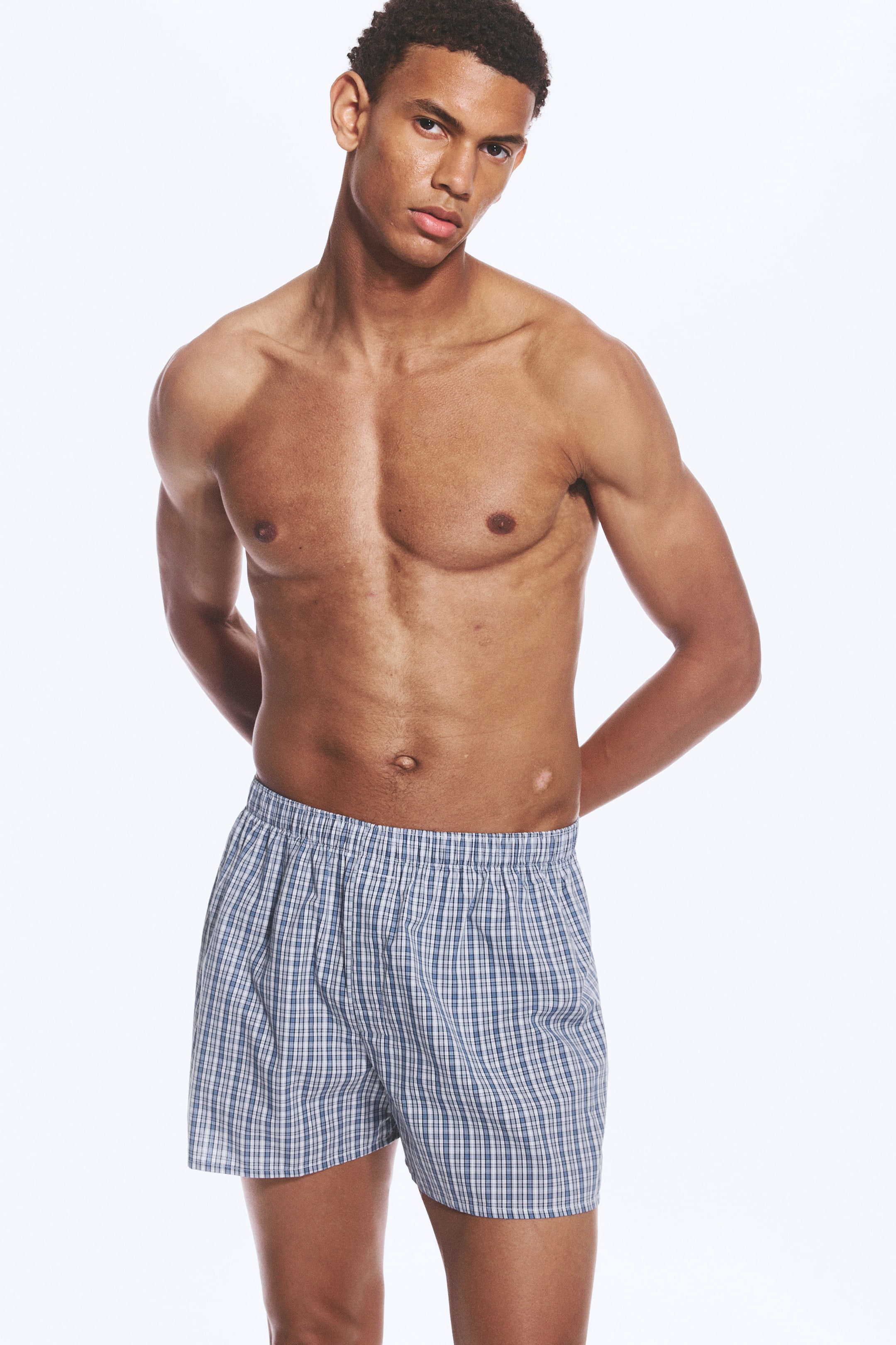 Größeres Bild anzeigen: Der/die Model trägt karierte Baumwoll-Boxershorts mit blau-weißem Karo-Muster und einem gerafften, elastischen Bund.