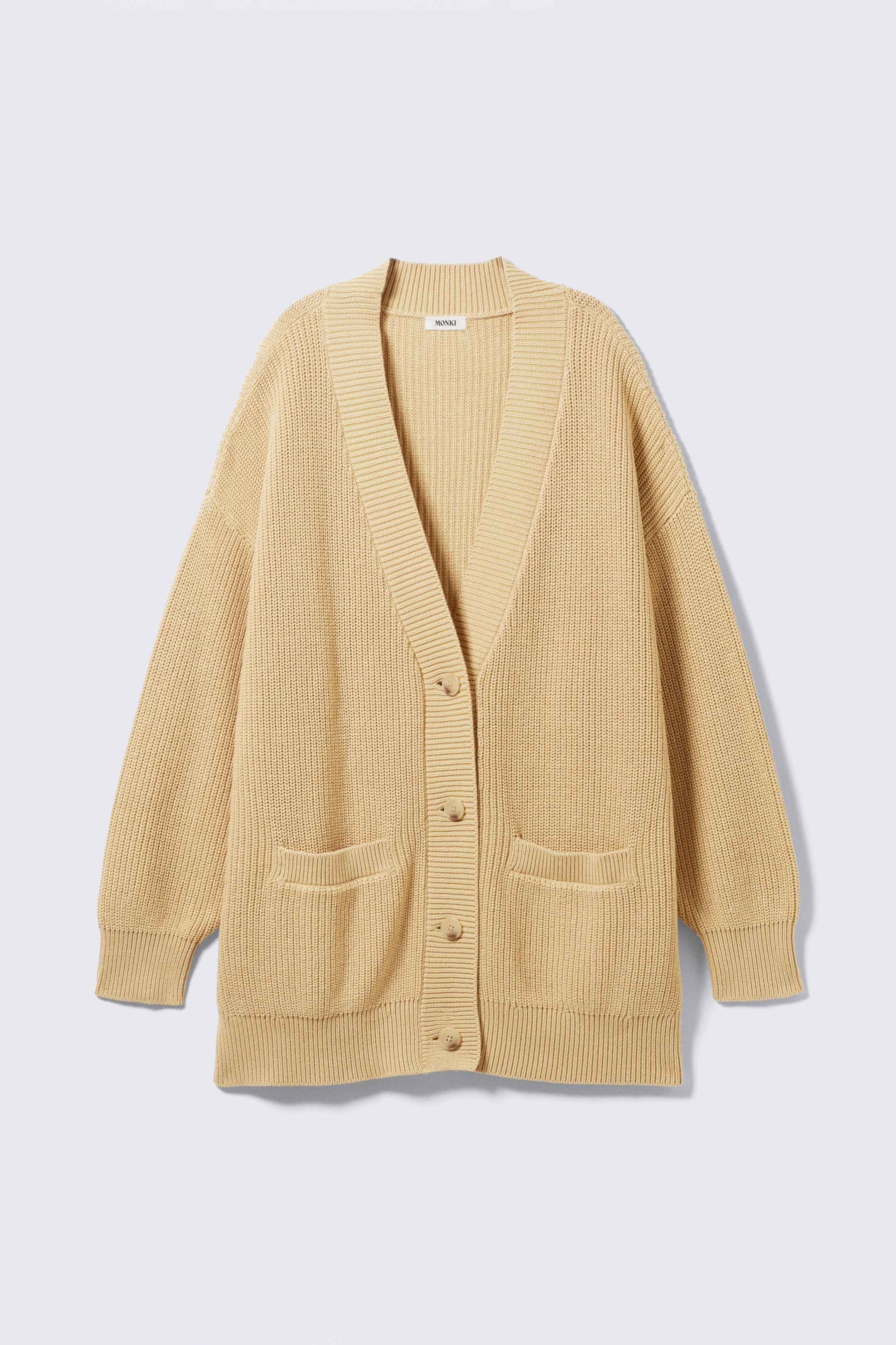 Grösseres Bild ansehen: Eine beige Strickjacke mit Rippenmuster zeigt sich nach vorne, flach ausgelegt, und präsentiert einen V-Ausschnitt mit einer breiten gerippten Knopfleiste und fünf runden, passenden Knöpfen, die vorne verläuft. Sie verfügt über zwei aufgesetzte Pattentaschen mit Rippenmuster an der unteren Front, lange Ärmel mit gerippten Bündchen und einen gerippten Saum.
