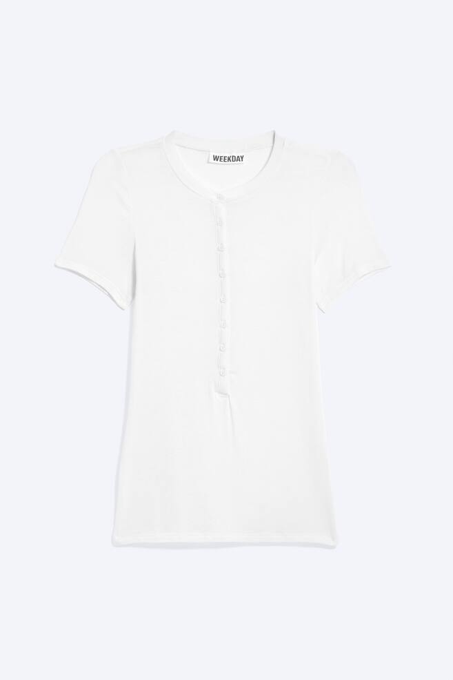 A white short-sleeved knitted top is facing front, featuring a round neckline, a partial front placket with eight small, round buttons, short sleeves, and a straight hem. - 1