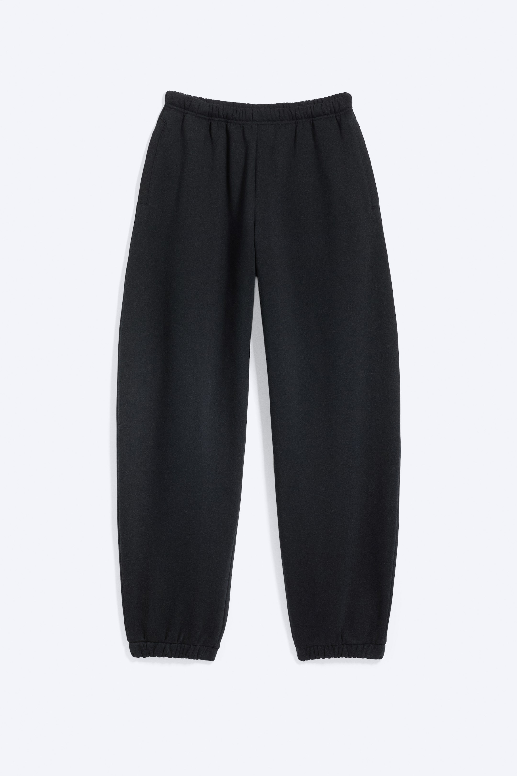 Agrandir l'image: Pantalon de jogging noir présenté en vue de face, avec une taille élastiquée, des poches latérales passepoilées et des jambes amples se rétrécissant vers des poignets élastiqués.