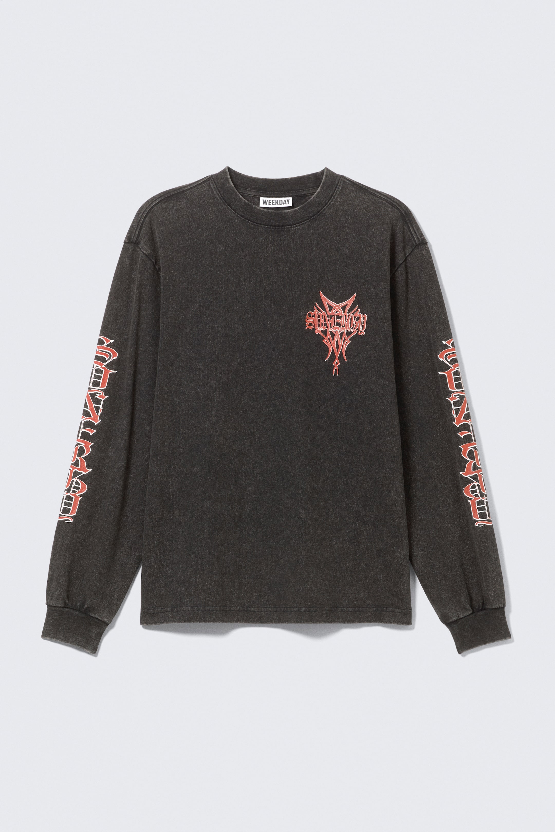 Grotere afbeelding bekijken: Een T-shirt met lange mouwen is van voren gefotografeerd en heeft een relaxed fit in gewassen zwart. Het heeft een geribde ronde hals, doorgezakte schouders, een rode grafische print op de borst en herhalende rode grafische prints langs beide mouwen, afgewerkt met geribde boorden.