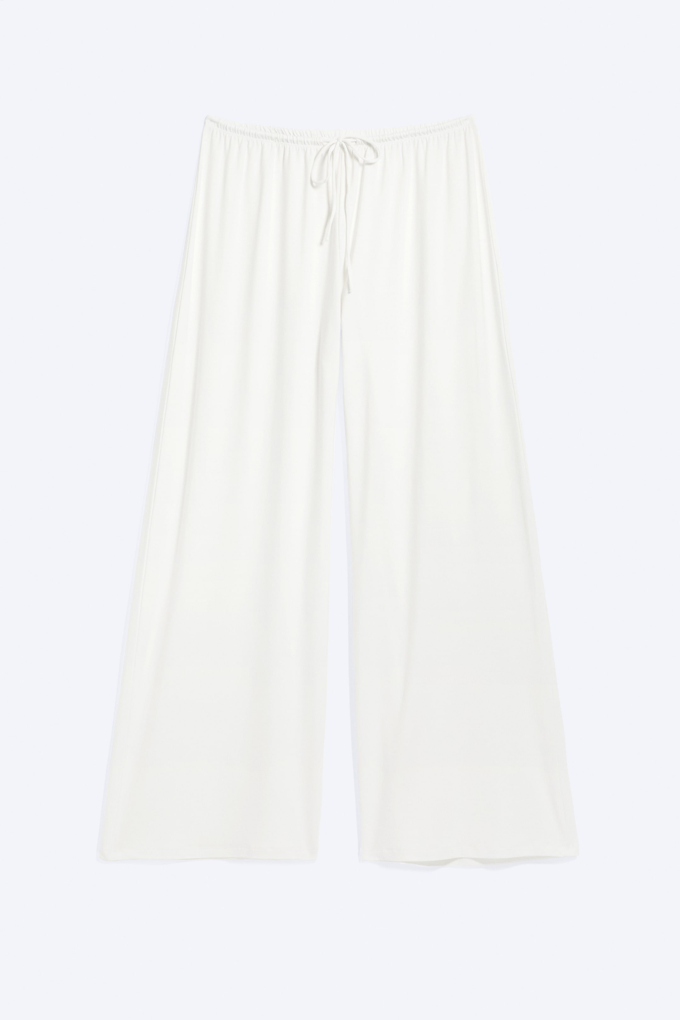 Visualizza l'immagine ingrandita: Un paio di pantaloni color crema chiaro è mostrato frontalmente, con una vestibilità ampia a gamba larga, una linea fluida e un elastico in vita con coulisse annodata al centro.