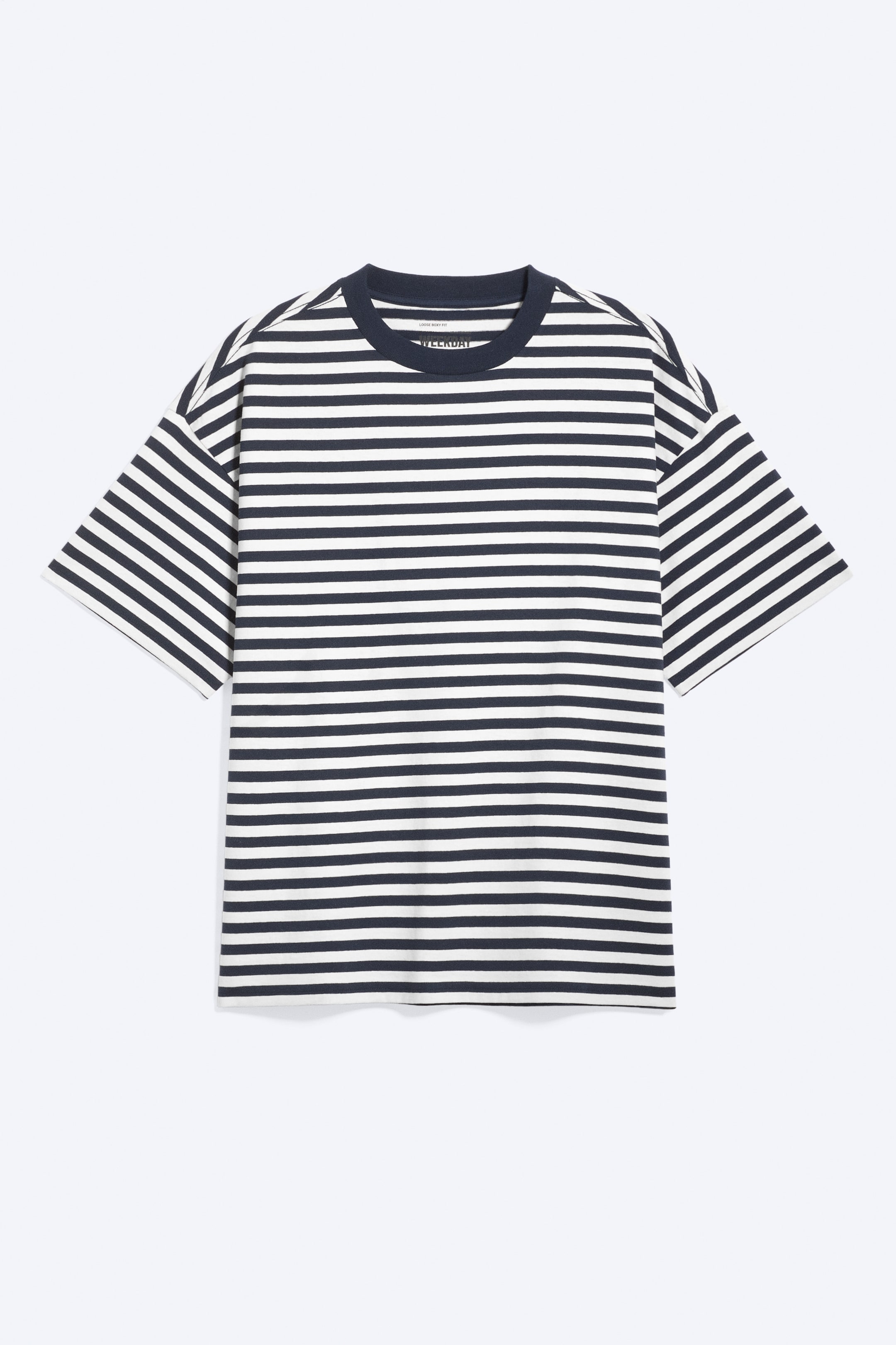Visualizza immagine più grande: Una t-shirt è mostrata di fronte, caratterizzata da righe orizzontali blu navy e bianche. È progettata con un girocollo, spalle scese e maniche ampie, mostrando una vestibilità oversize e comoda.