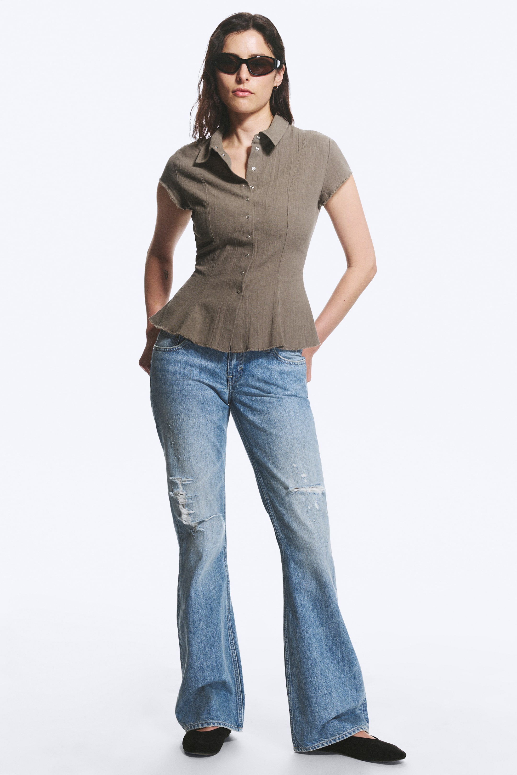 Grotere afbeelding bekijken: Lichtblauwe flared jeans met een versleten look, voorzien van opvallende scheuren en slijtageplekken op de dijen en knieën, bieden een relaxte pasvorm met een wijde pijpopening.
