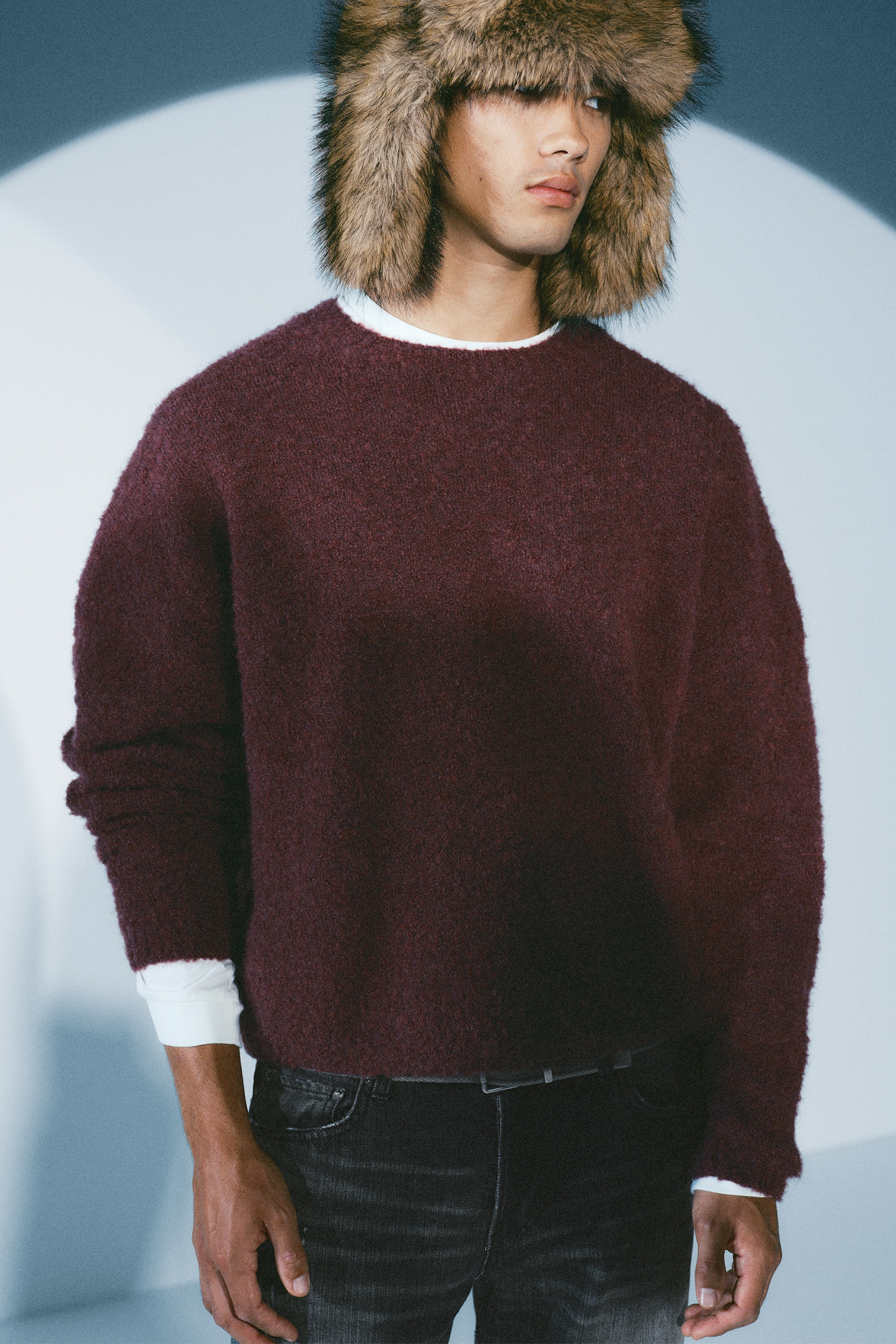 Uma camisola burgundy de gola redonda estÃ¡ a exibir uma construÃ§Ã£o em malha texturada e fofa na parte da frente. A peÃ§a apresenta um corte descontraÃ­do, uma clÃ¡ssica gola redonda e mangas compridas com punhos e bainha de acabamento limpo.