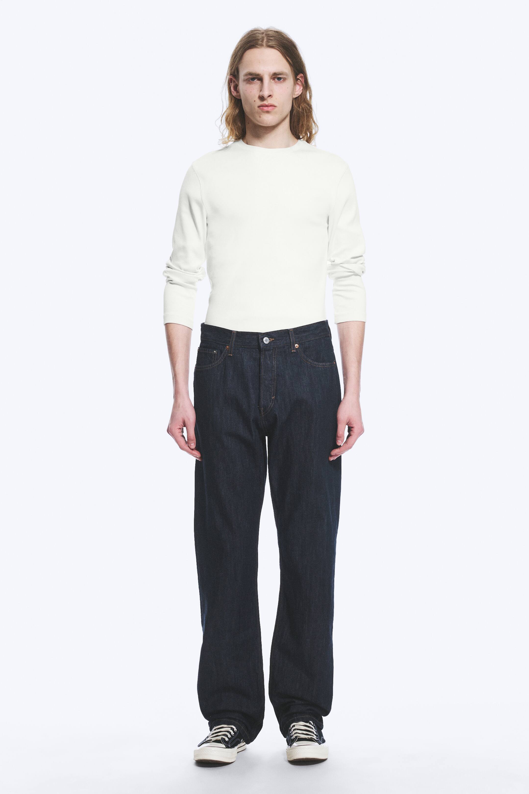 Vezi imaginea mai mare: Blugi din denim cu spălare închisă sunt prezentați dintr-o vedere frontală, având o croială relaxată, cu picior drept și stil clasic cu cinci buzunare și cusături contrastante, cu o închidere vizibilă cu nasturi la talie, iar tivul se așază peste pantofi.