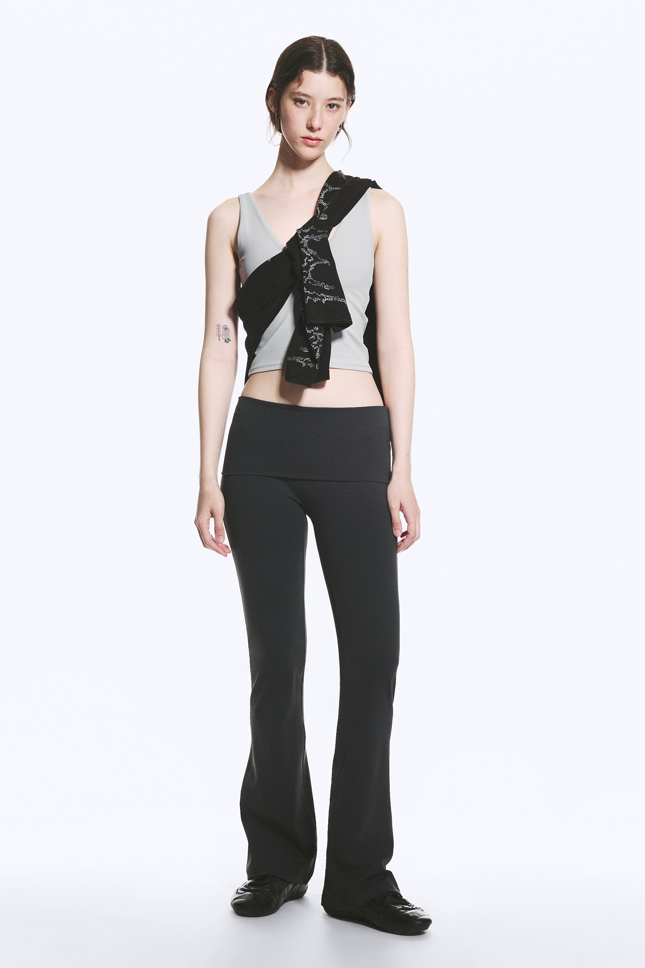 Visa större bild: Ett par svarta slim-fit, hellånga tights bärs av modellen. Dessa tights har en bred, vikt hög midjeband och utsvängda ben.