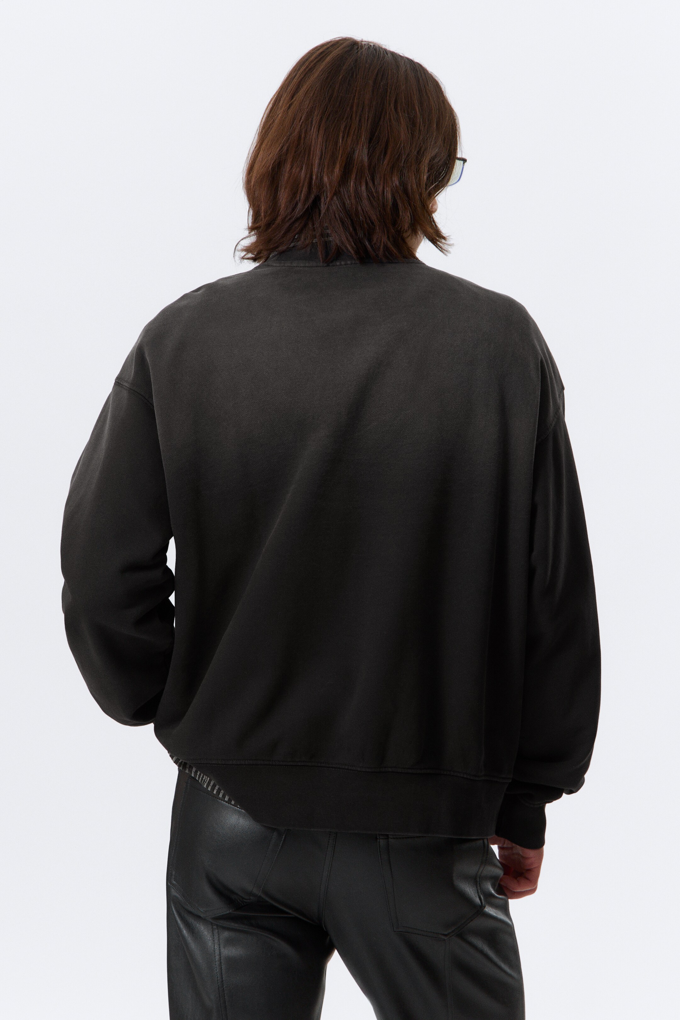 Grotere afbeelding bekijken: Een donkere, gewassen zwarte sweatshirt wordt van de achterkant getoond. Het heeft een ontspannen pasvorm met geribbelde boorden en een geribbelde zoom.