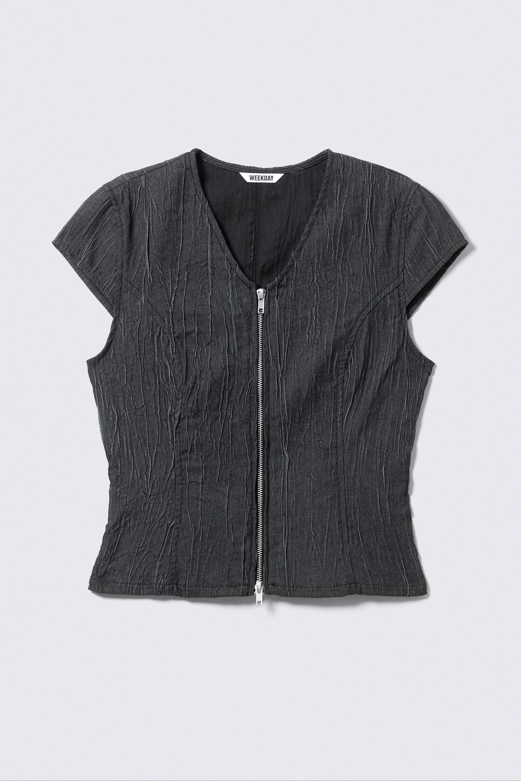 View larger image: A front view of a dark gray, cap-sleeved top is showcasing a distinct crinkled texture across its fabric, featuring a V-neckline and a full-length, silver-toned zipper closure at the front.