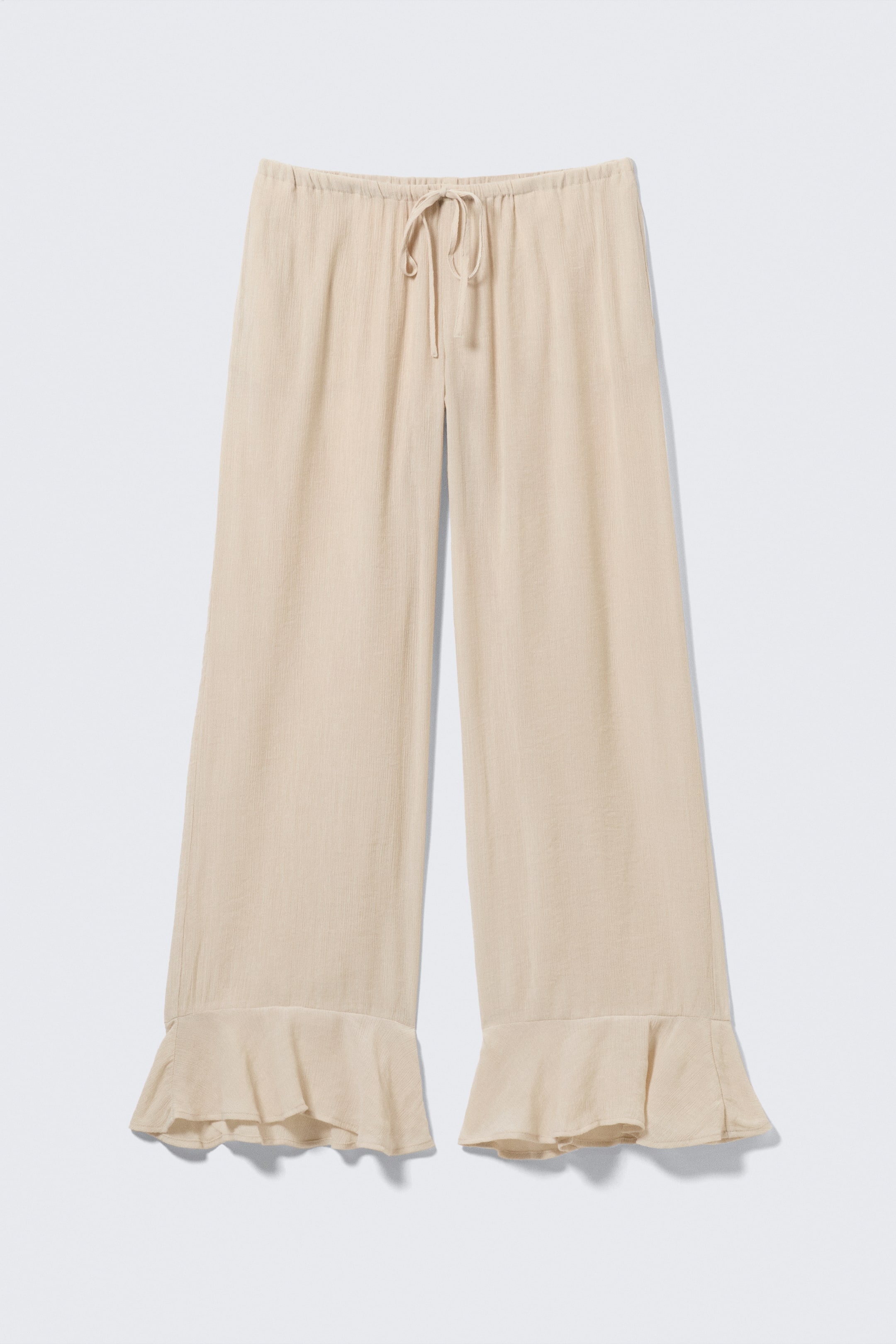 Visualizza l'immagine ingrandita: Un paio di pantaloni beige chiaro, a vestibilità ampia, mostrati frontalmente, caratterizzati da una texture stropicciata, una fascia elastica in vita con laccetti e orli arricciati.