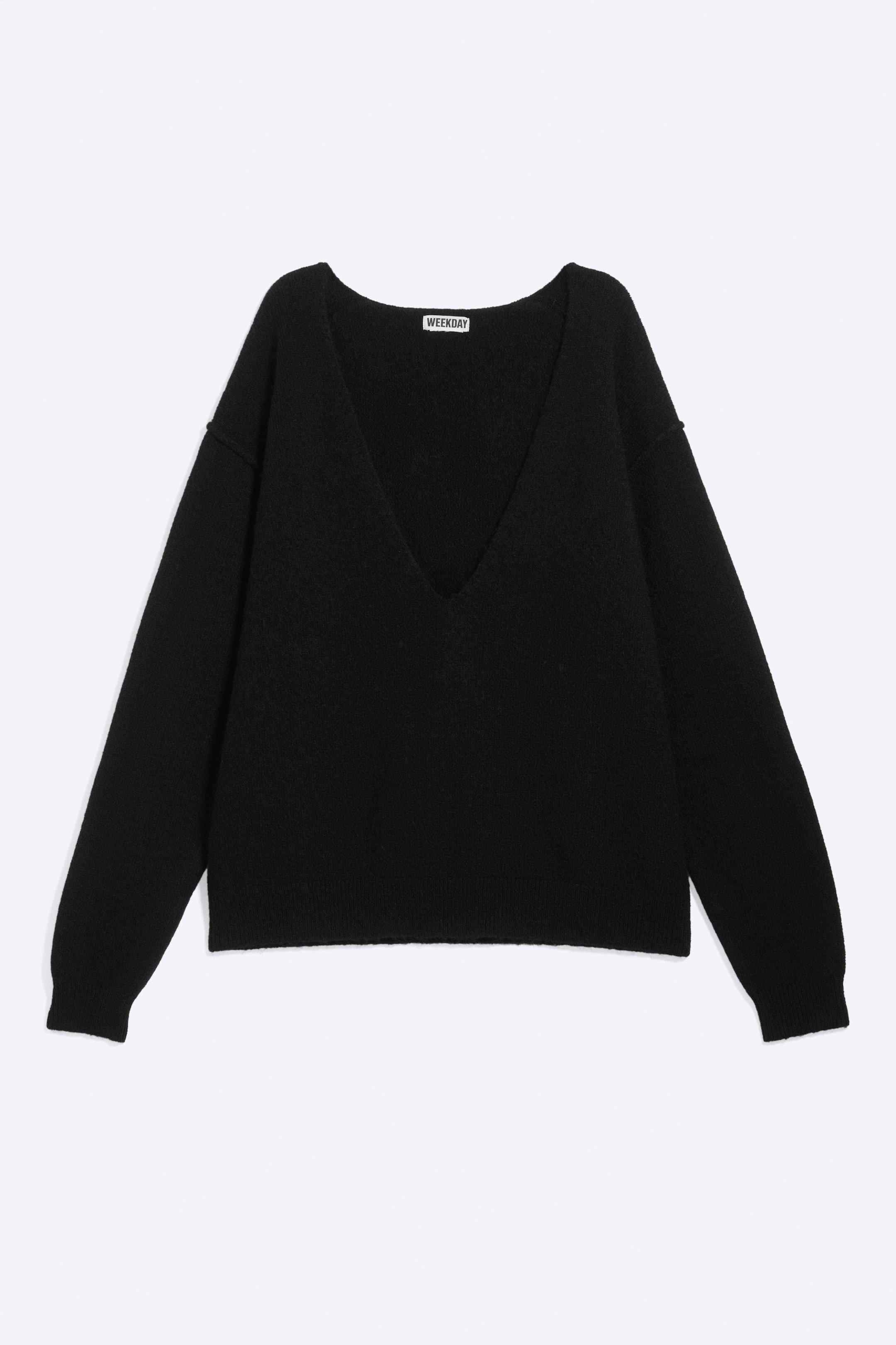 Agrandir l'image: Un pull noir est présenté de face, mettant en valeur un profond décolleté en V, des manches longues avec des poignets côtelés et un ourlet inférieur côtelé. Le pull présente une coupe ample et un matériau en maille texturée.