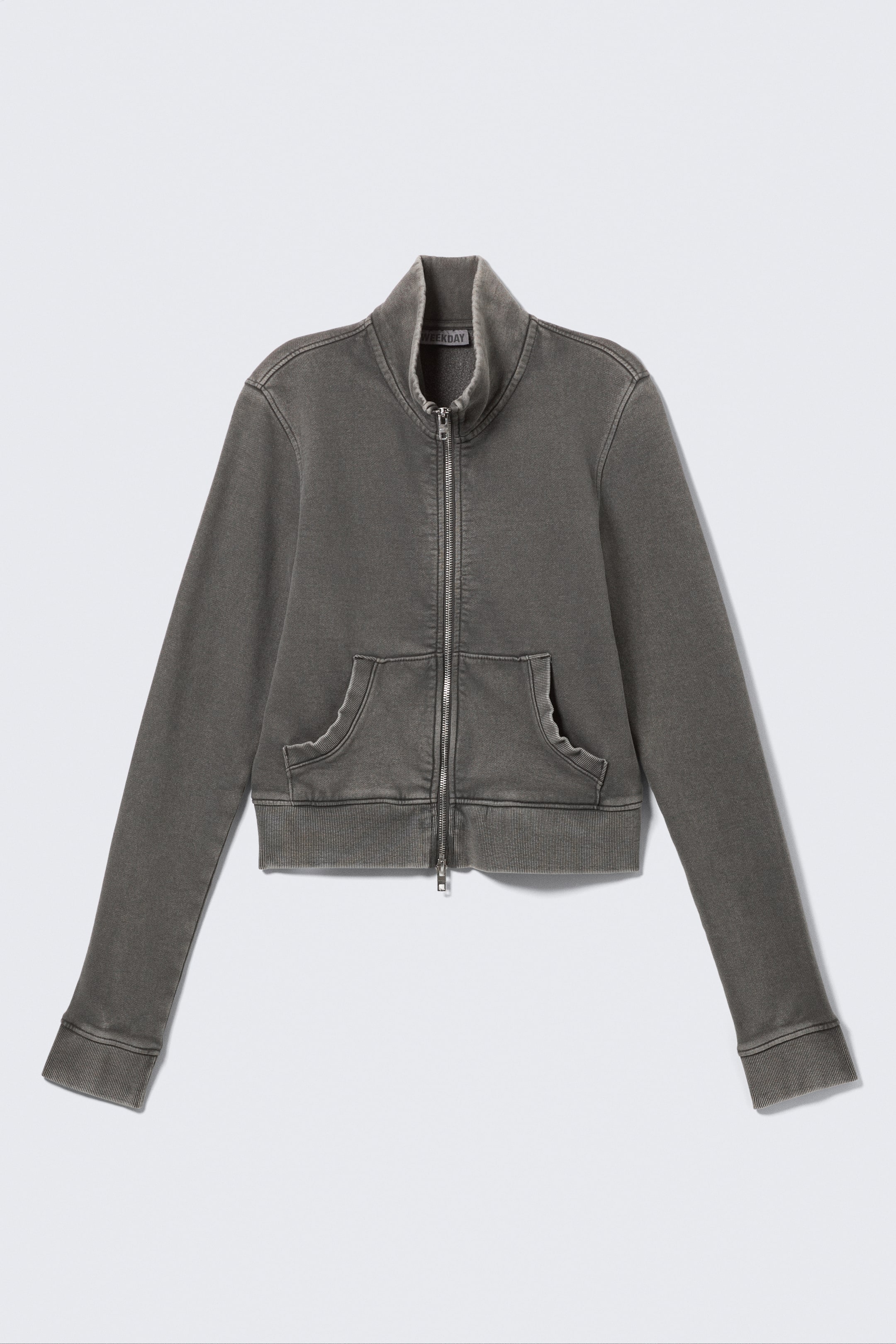 View larger image: A cropped, faded charcoal full-zip jacket is presented from the front, featuring a high stand-up collar, a silver-toned zip down the centre and two patch pockets above a ribbed hem. The long sleeves end in ribbed cuffs.