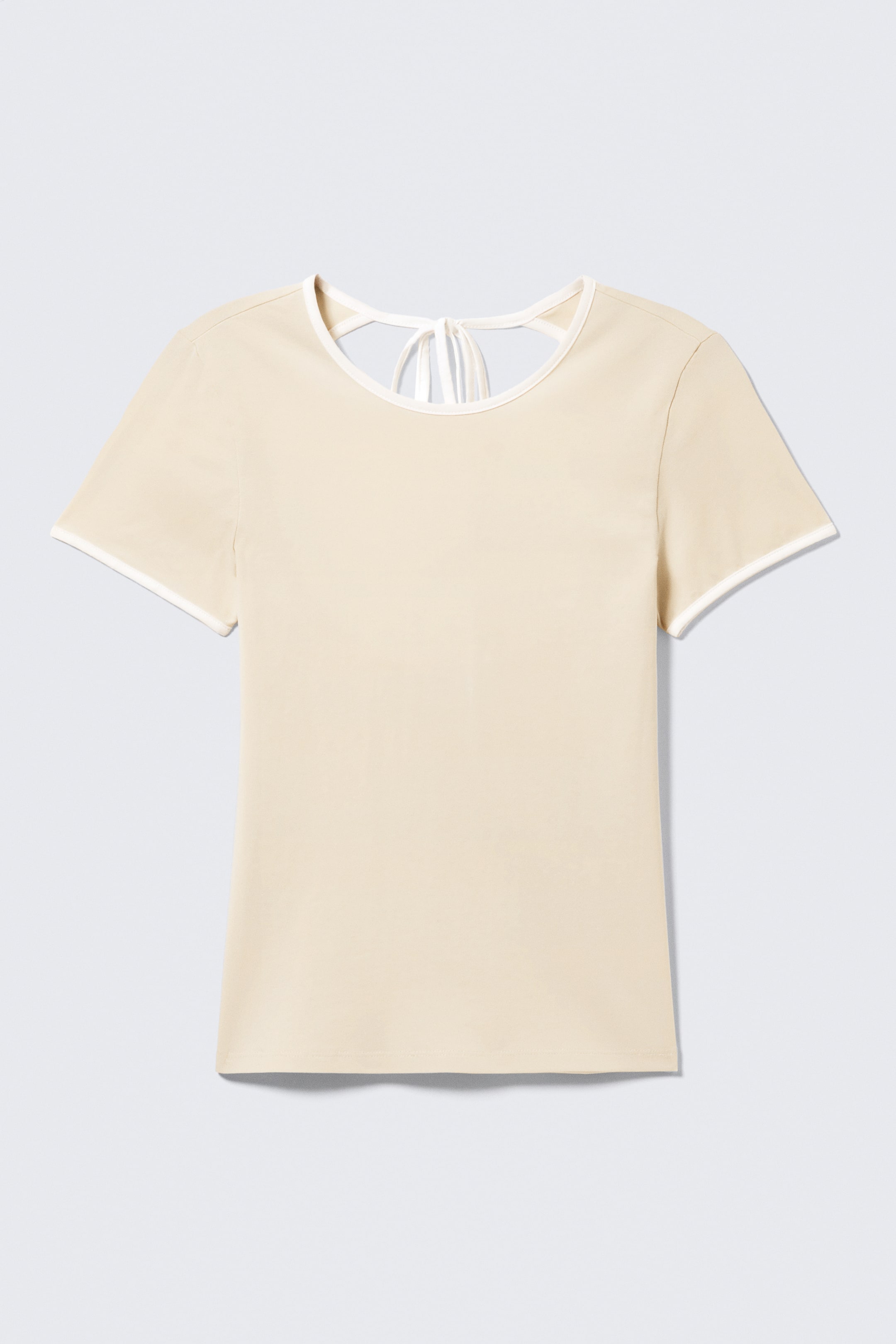 Agrandir l'image: Un haut ajusté, beige clair, à manches courtes, doté d'un col rond et d'un passepoil blanc le long de l'encolure et des ourlets des manches. Au dos du cou, deux liens blancs sont visibles, suggérant un design à dos ouvert.