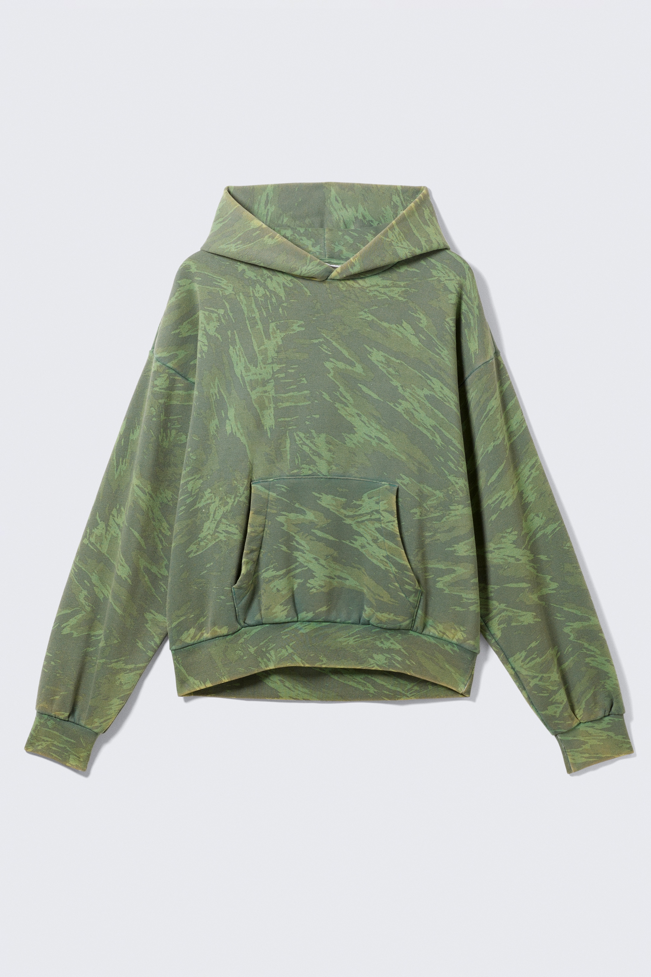 Grotere afbeelding bekijken: Een loszittende grafische hoodie toont zijn VOORZIJDE, met een groen abstract penseelstrekenpatroon. Het is ontworpen met verlaagde schouders, een ruime capuchon, een kangoeroezak en geribbelde manchetten en zoom.