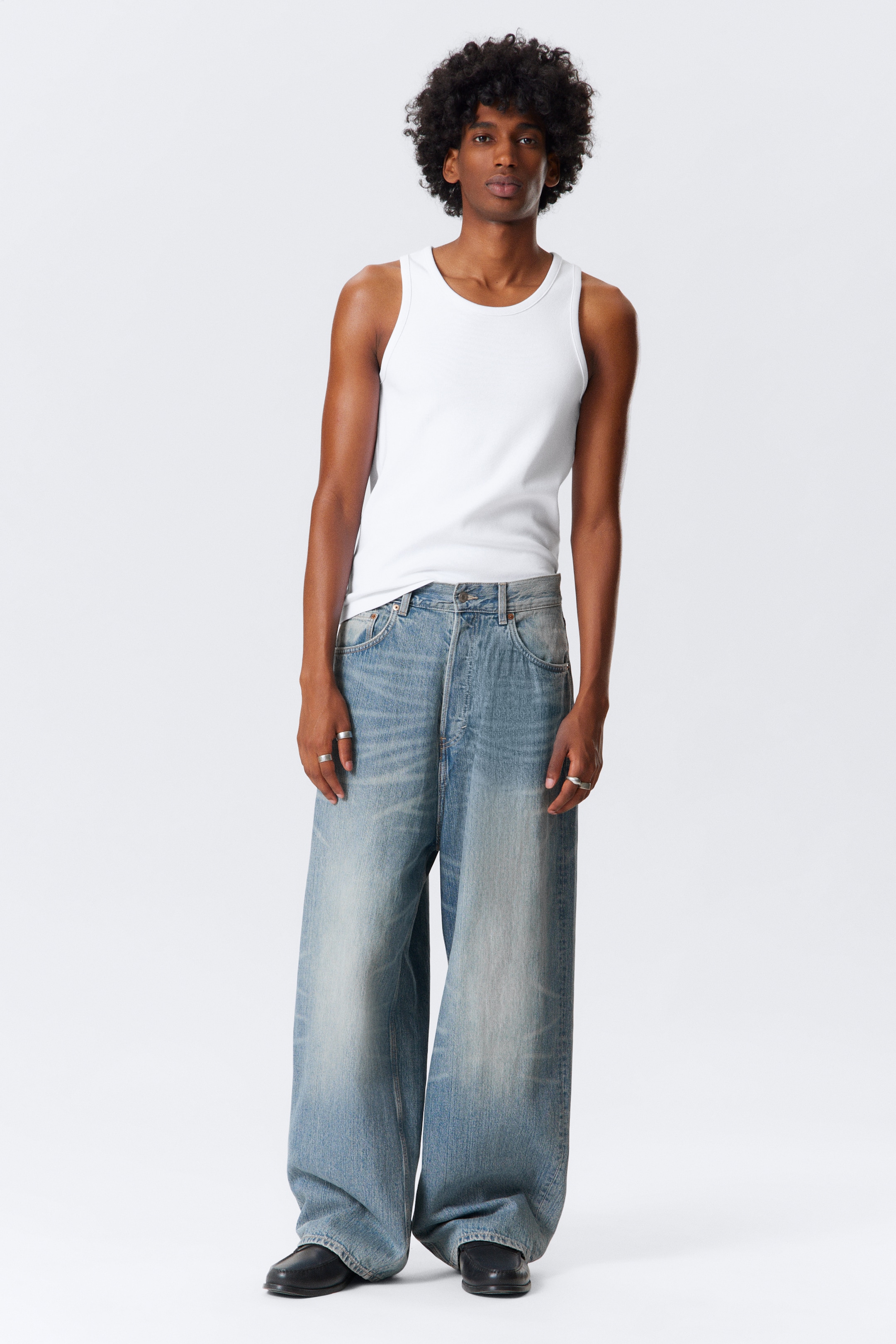 View larger image: A white ribbed tank top is being worn, featuring a crew neck and a close fit. It is paired with light wash, wide-leg jeans that are designed with a relaxed, baggy silhouette.