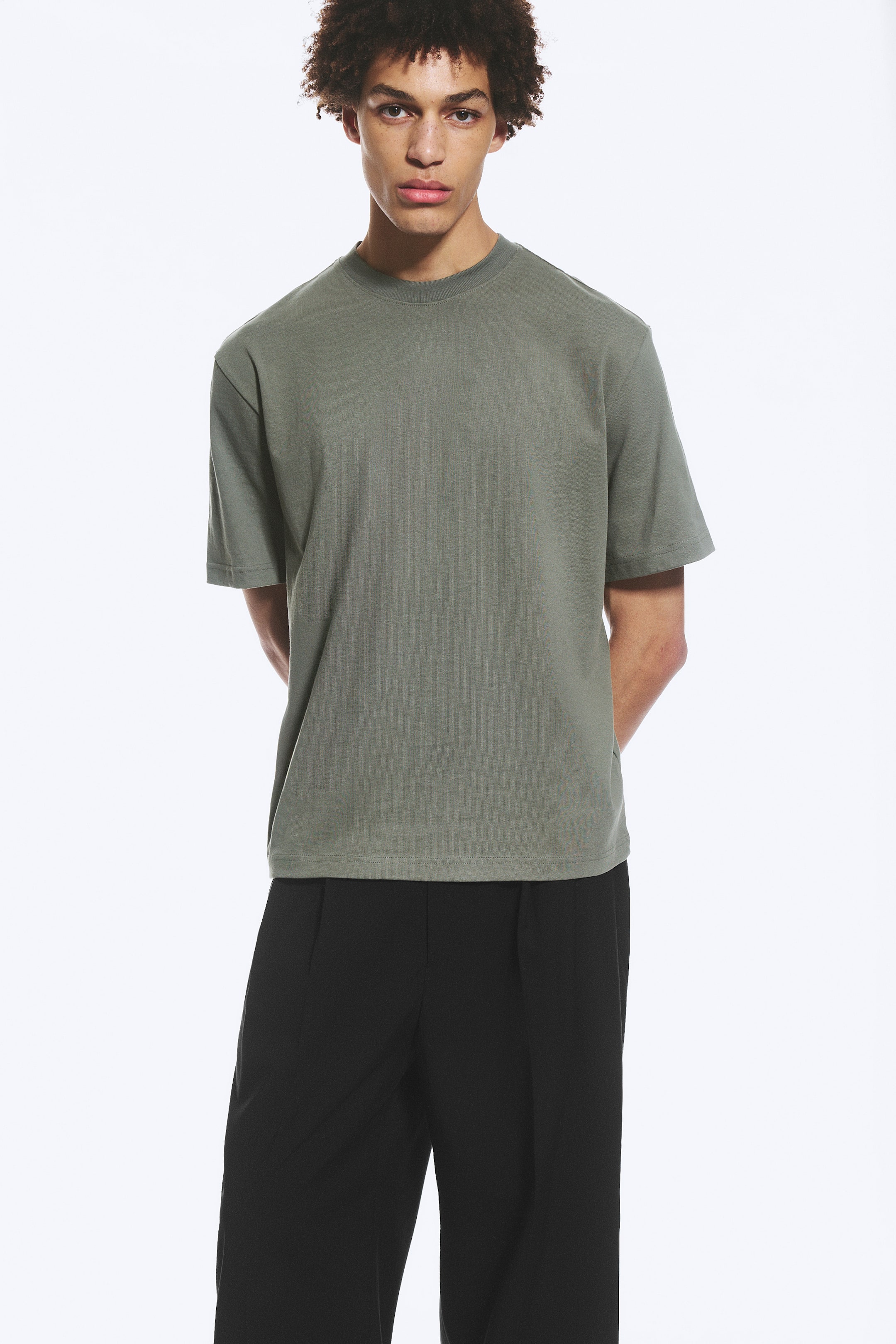 Agrandir l'image: Le t-shirt vert sauge présente un col rond côtelé et des manches courtes. Il offre une coupe décontractée et s'étend jusqu'aux hanches.
